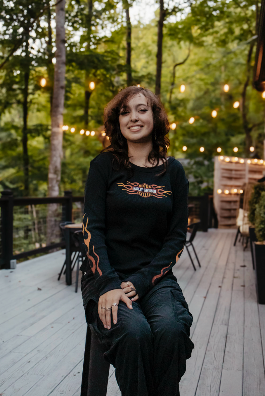 A sequence of artistic portraits showing a person in black clothing posing on a wooden deck with string lights in background.