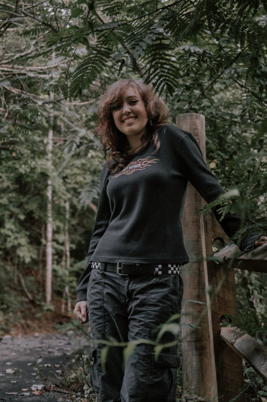 Artistic outdoor portrait session in a wooded setting with someone wearing all black attire against lush greenery.