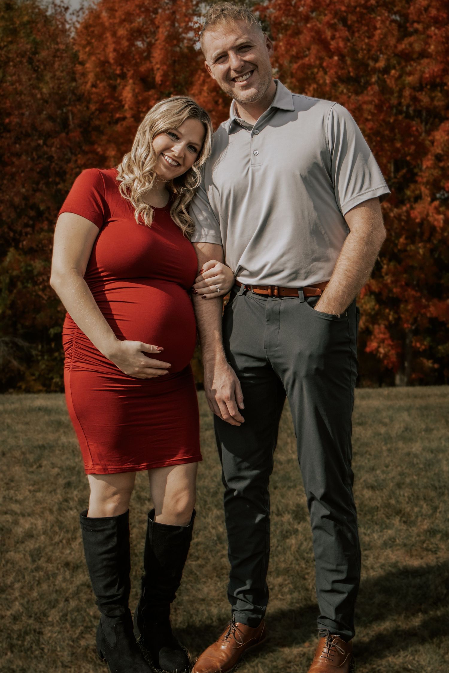 A couple poses together against a backdrop of vibrant fall foliage.