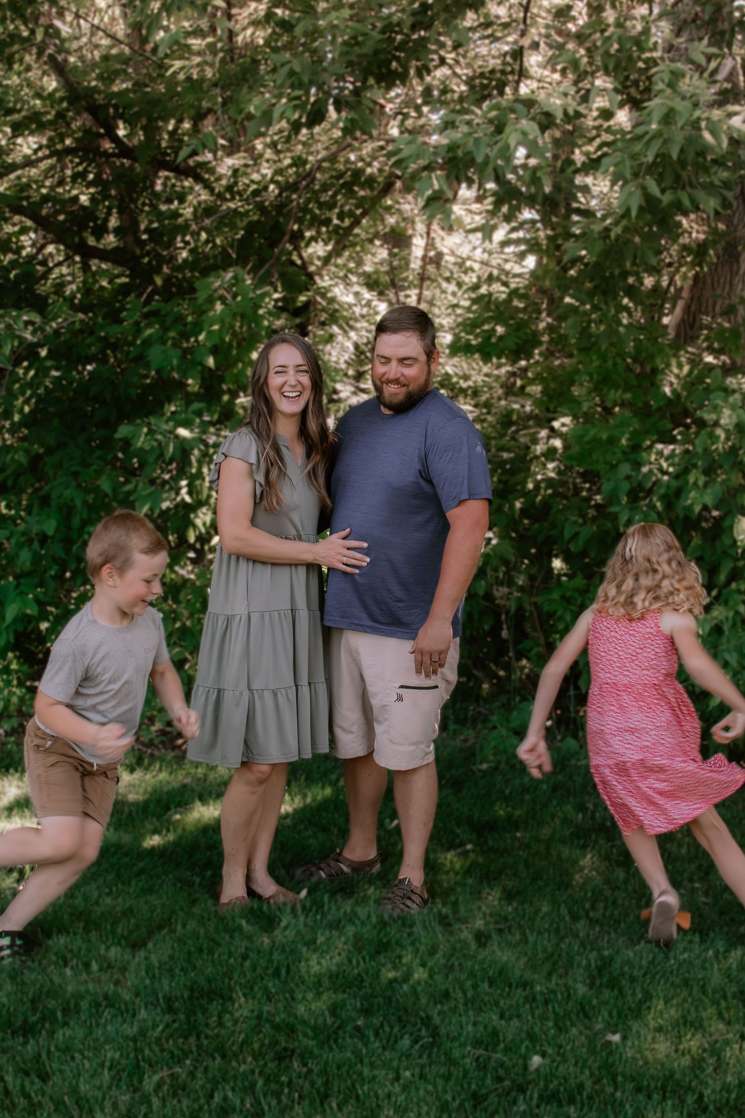 Happy family with two young children playing outdoors in a lush green backyard during summer.