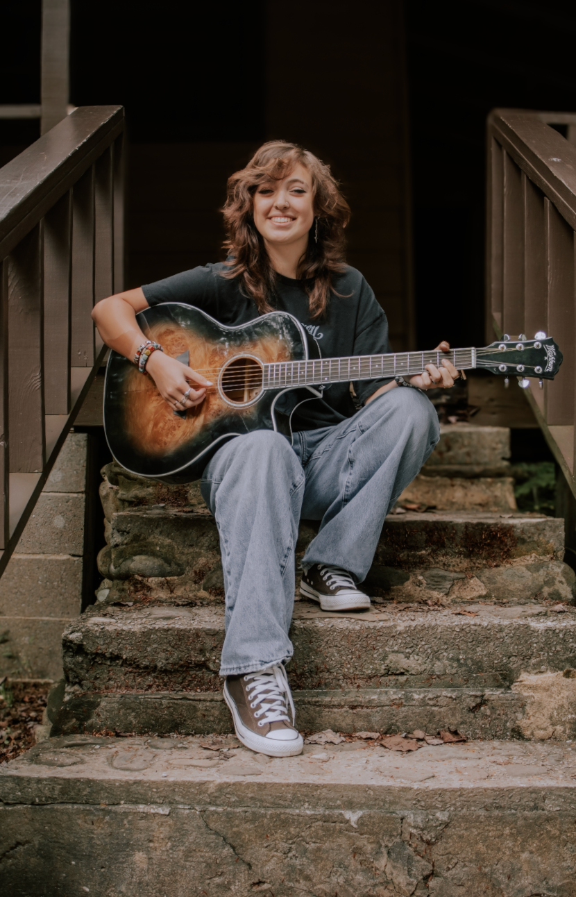 Close-up sequence showing someone sitting on stone steps playing an acoustic guitar while wearing jeans and sneakers.