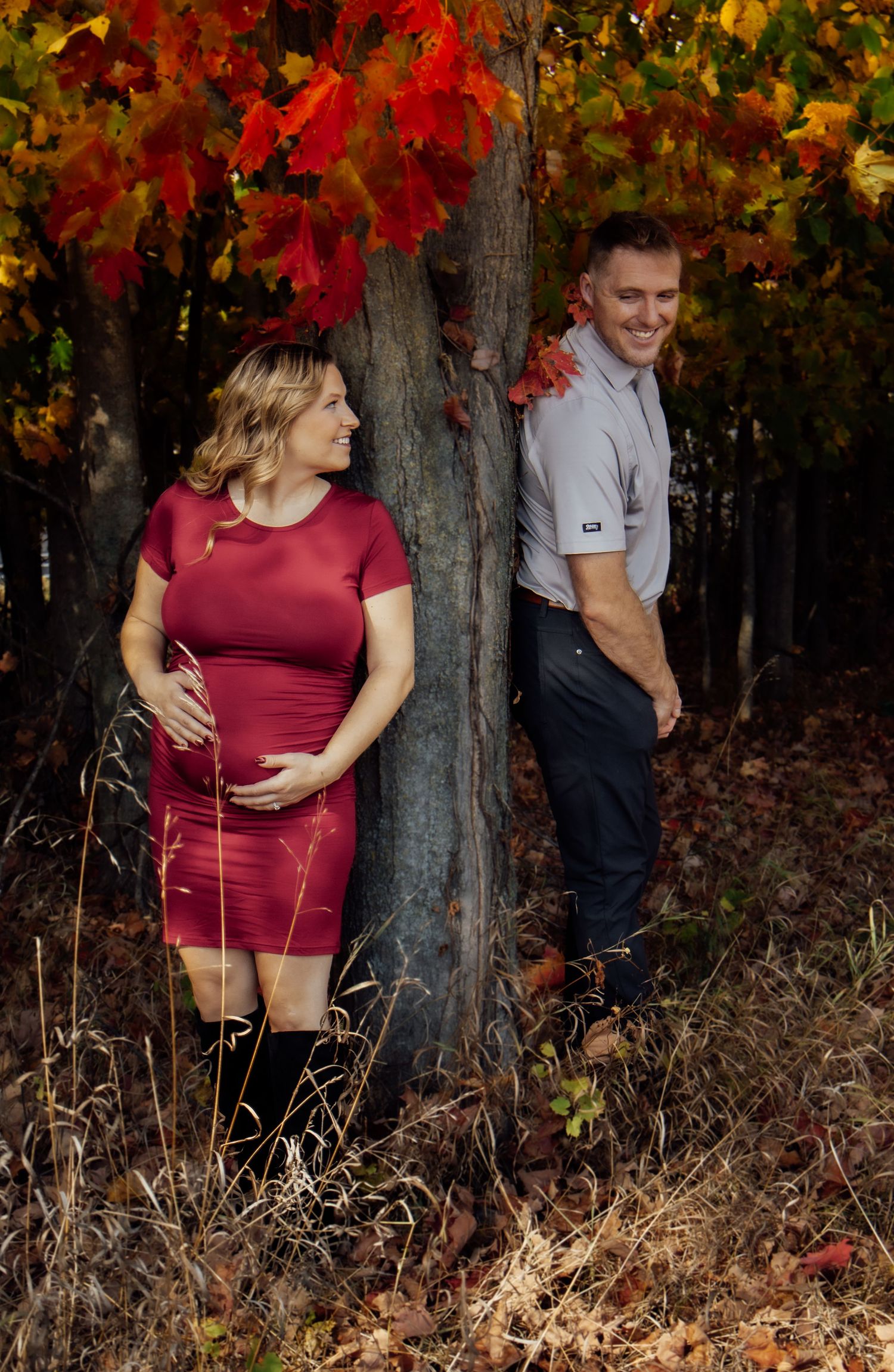 Autumn maternity session with vibrant red foliage and natural woodland setting.