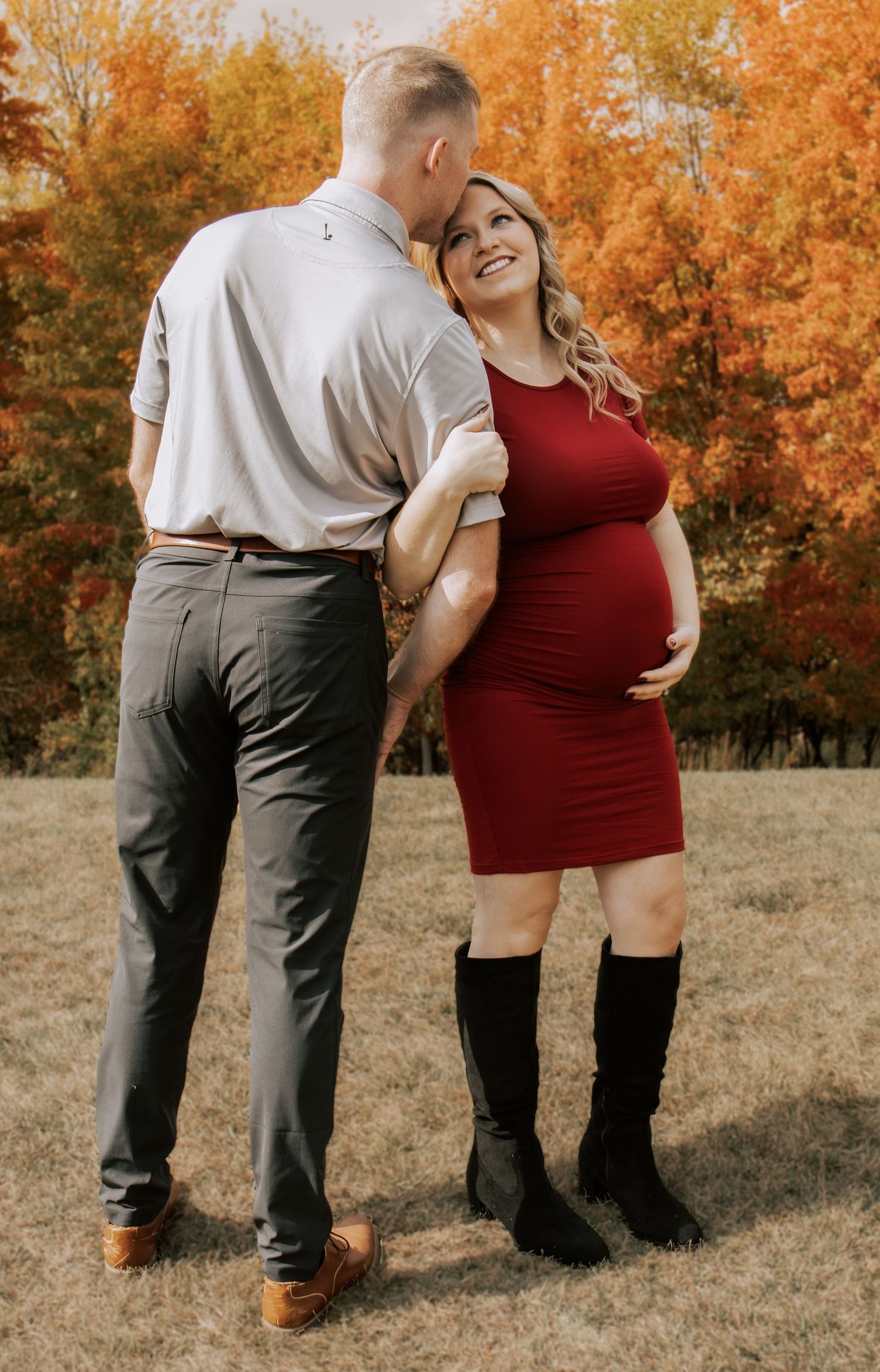 Playful maternity portraits captured against golden fall trees and grass.