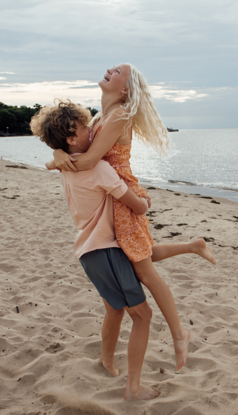 A romantic beach photoshoot sequence shows a couple embracing and playing in the sand at sunset.