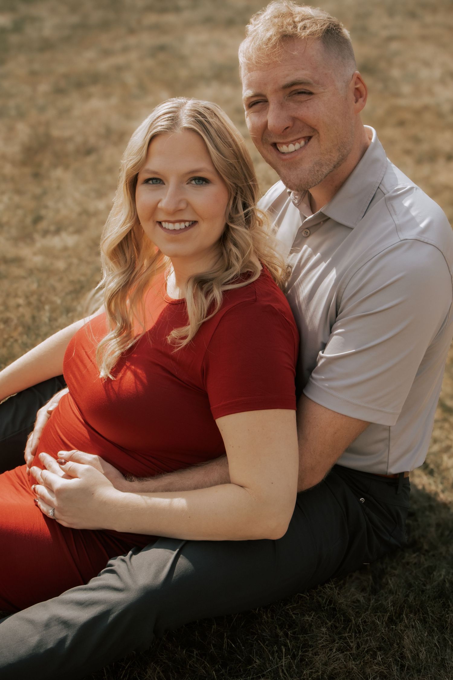 A couple embraces on a grassy field during a romantic autumn photoshoot.