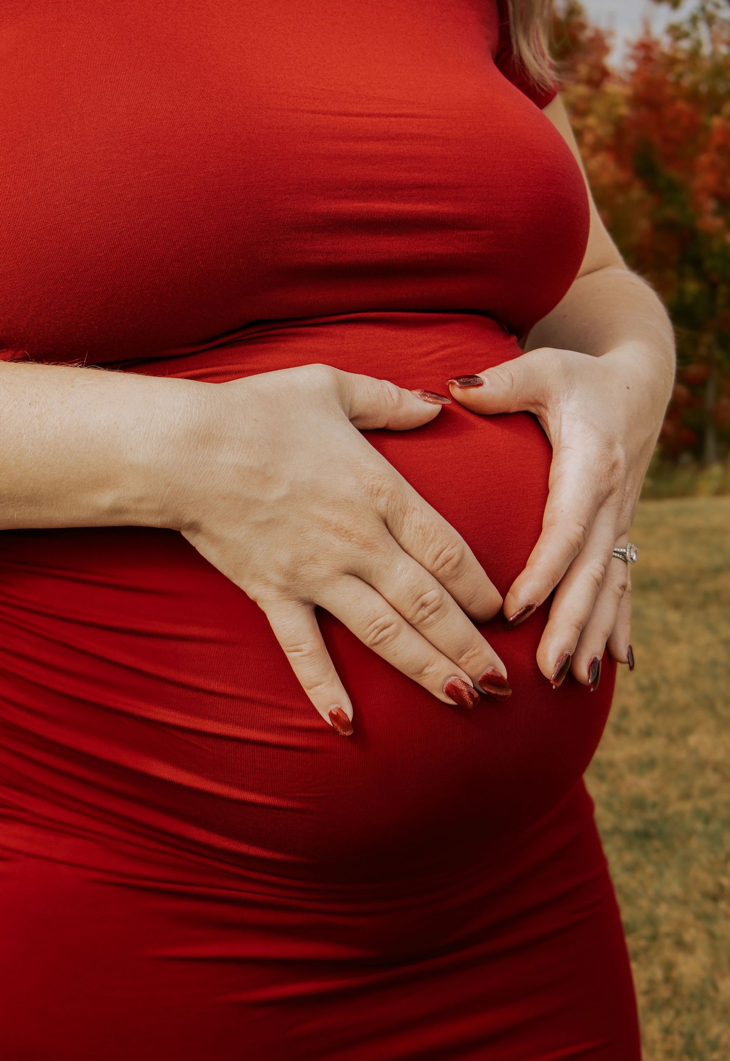 A series of maternity photos showing a pregnant belly in a red dress against an autumn background.