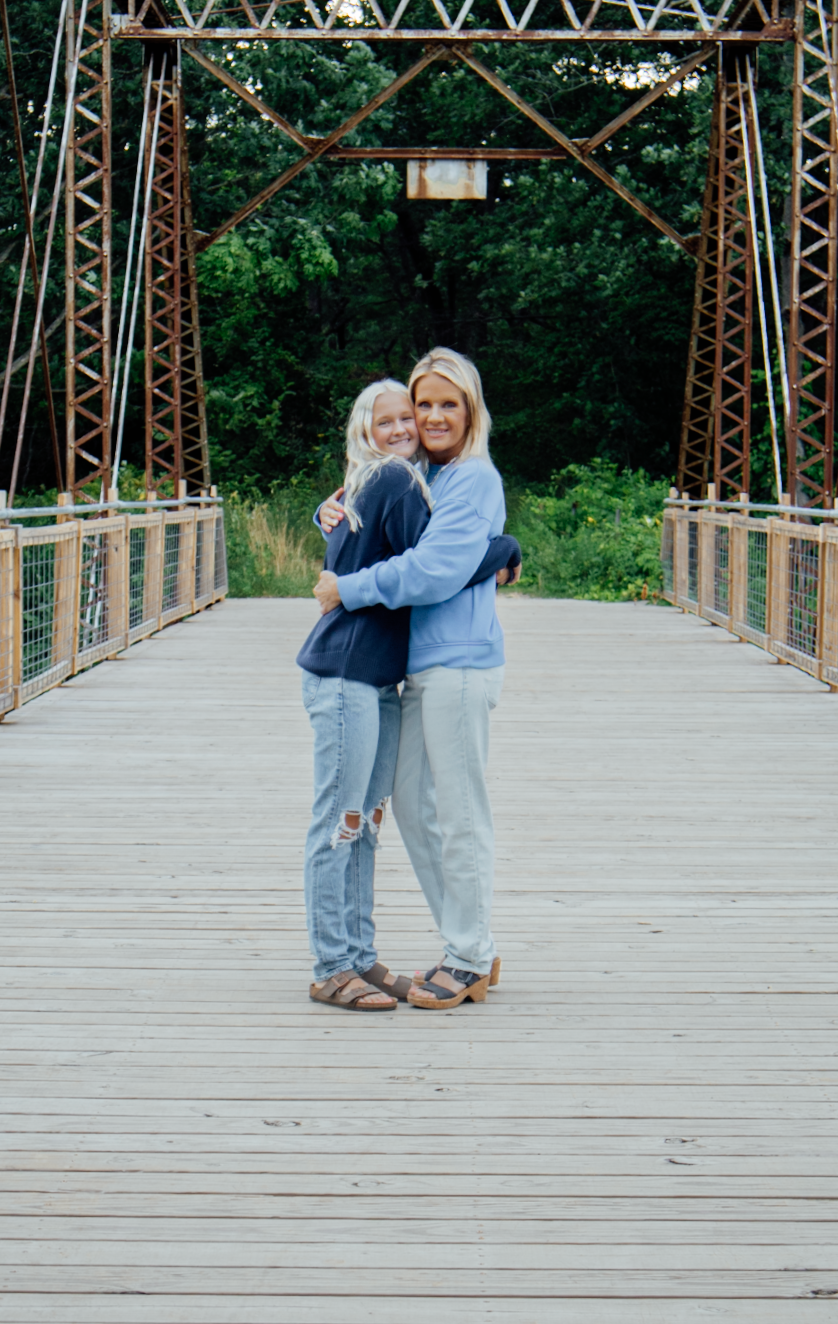 Couple sharing a romantic dance moment on a wooden bridge surrounded by metal trusses and green foliage.