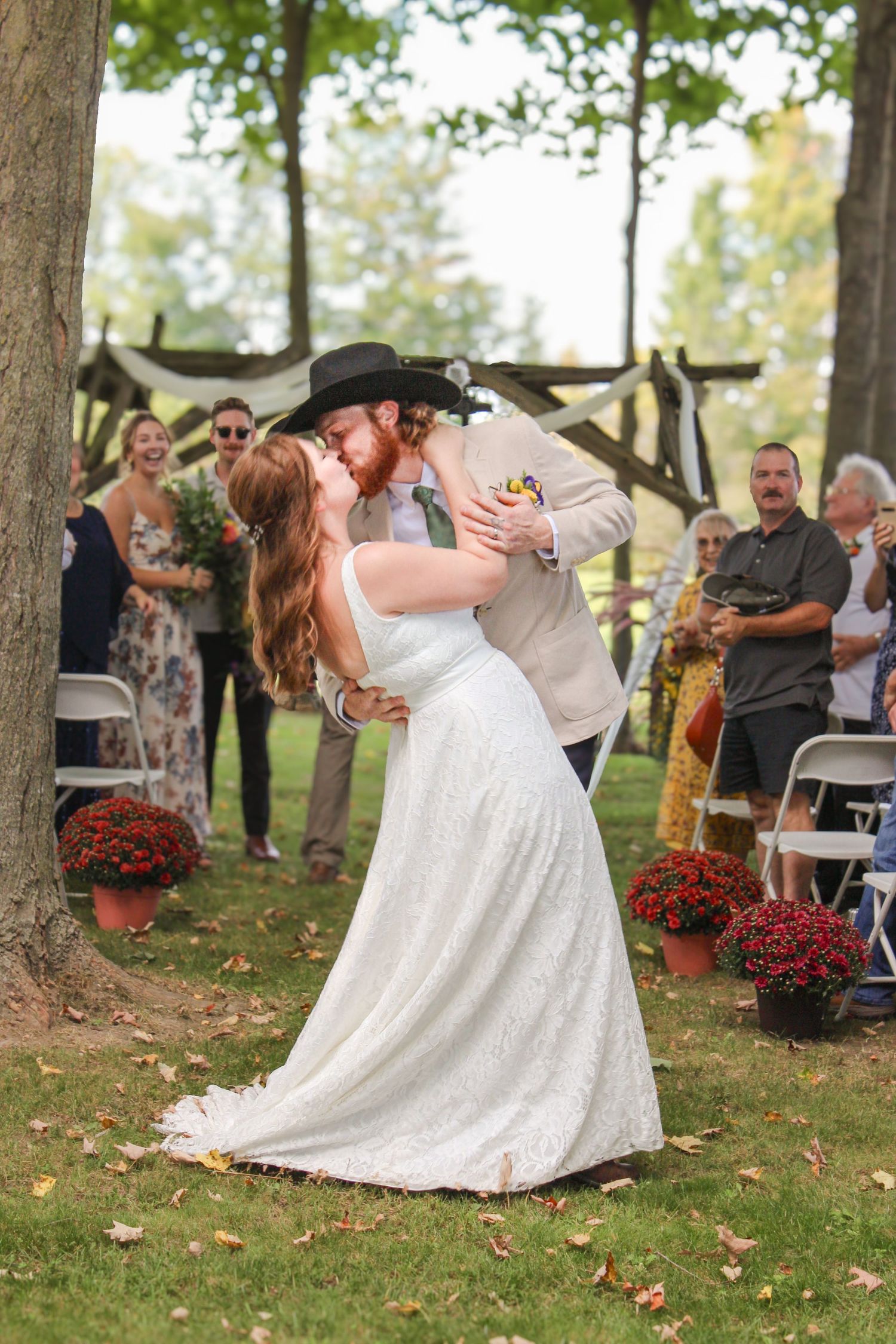 Bride and groom share first kiss as recessional with guests cheering in background.