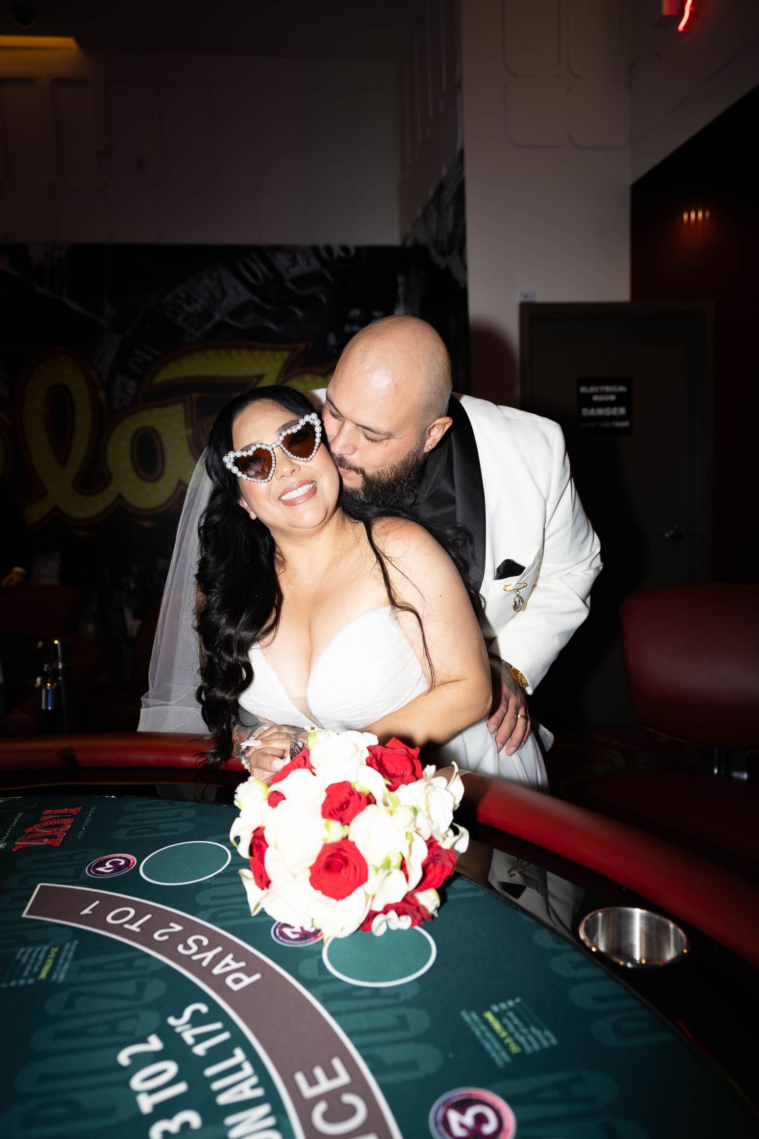 A happy couple during an elopement enjoying a kiss on the cheek over a poker table giving ultimate las vegas wedding vibes with happy smiles