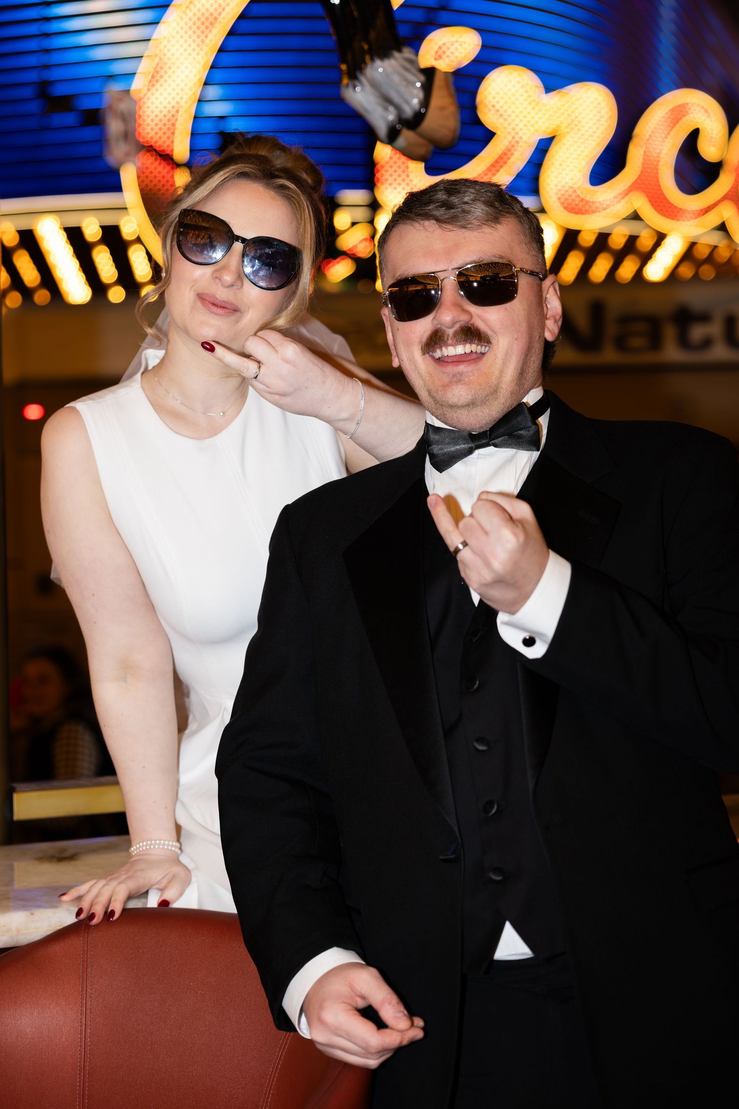couple posing in sunglasses and formal attire during a fun Las Vegas elopement photo session under the city lights
