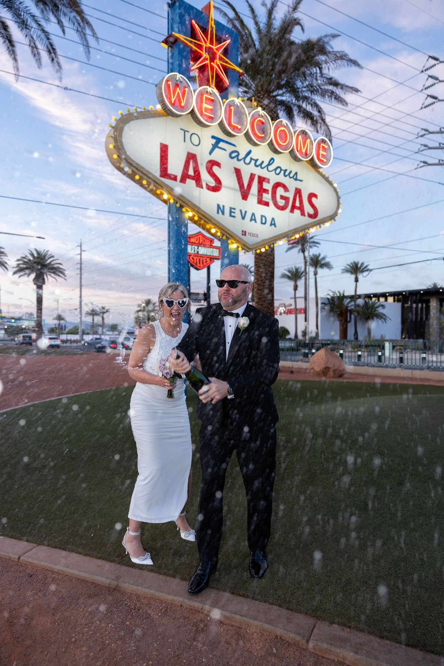 Bride and Groom popping champaign to celebrate their iconic Las Vegas Elopement in the city with excitement on their faces
