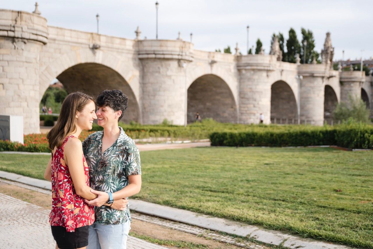 Couple standing by the historic Toledo Bridge in Madrid during an engagement photography session.