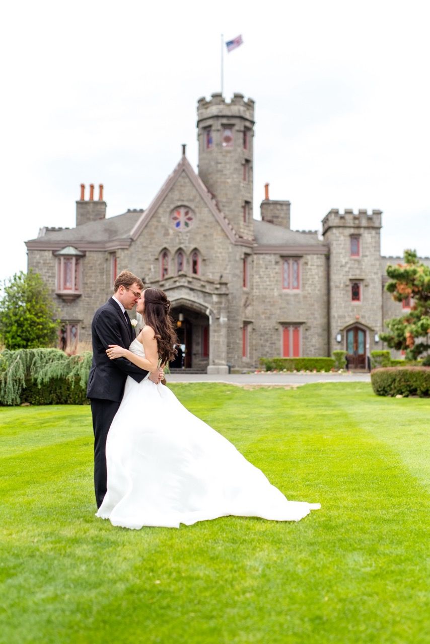 A romantic moment captured on the lawn of a majestic stone castle with towers and turrets.