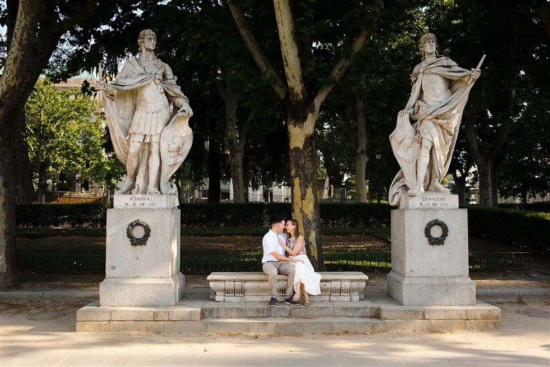 Stone statues and sculptures line a tree-shaded path outside of Royal Palace of Madrid, Spain.