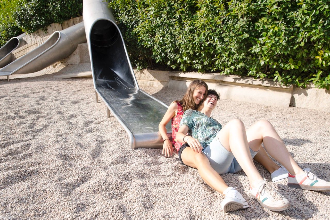 Couple relaxing at a modern playground slide in a Madrid park setting.