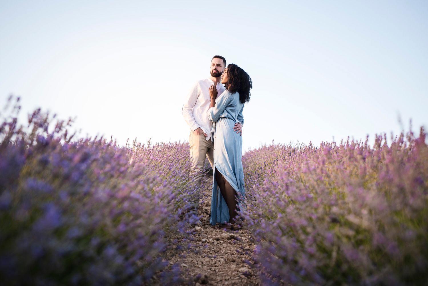 Romantic couple embracing in beautiful purple lavender field at sunset.
