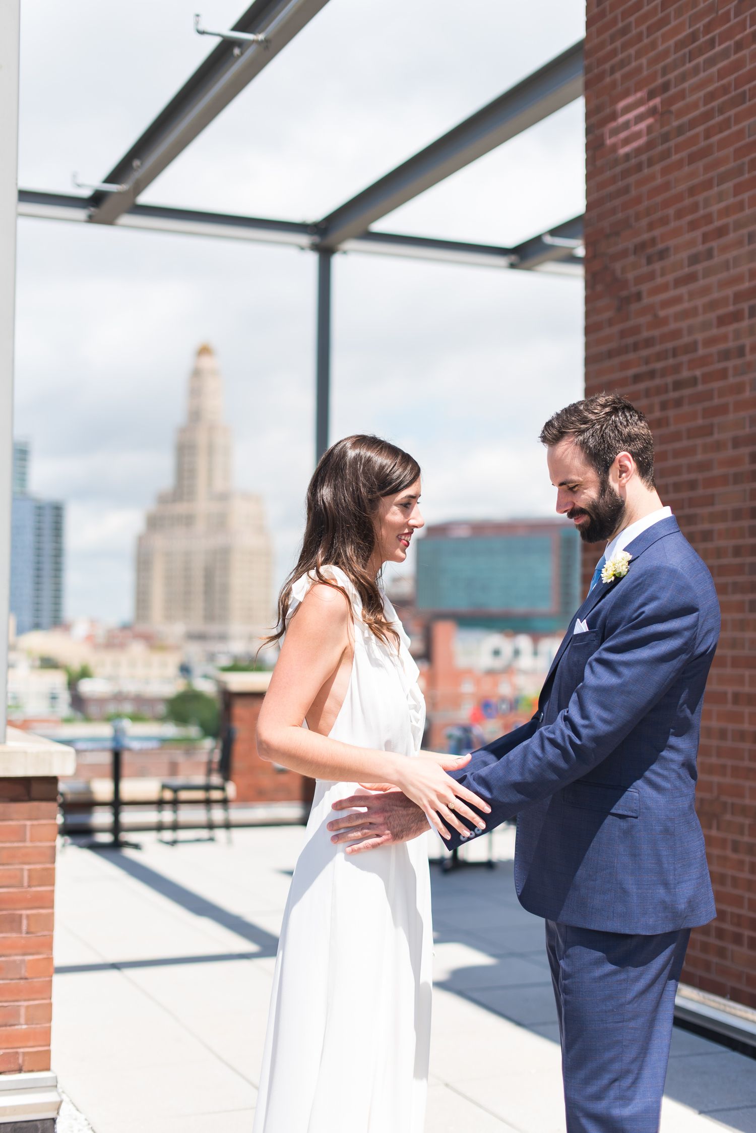 Wedding couple sharing an intimate moment on a rooftop with city skyline in background.