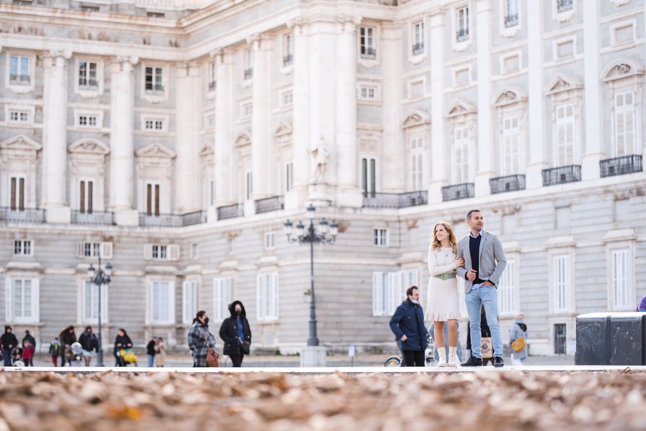 White neoclassical facade of Royal Palace of Madrid with tourists in foreground.