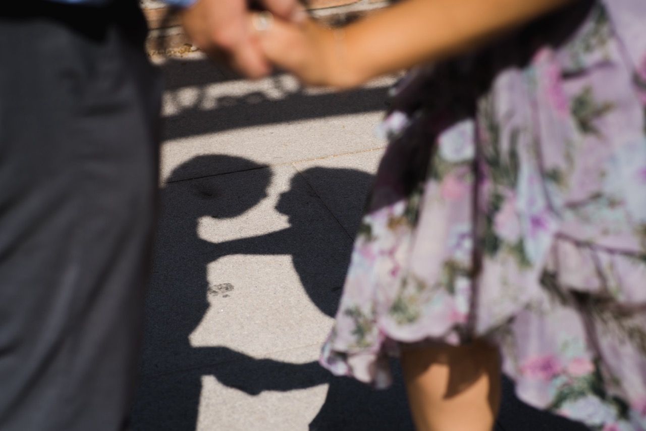 Creative engagement proposal photo of silhouette of two people casting shadows on the ground during a sunny day.