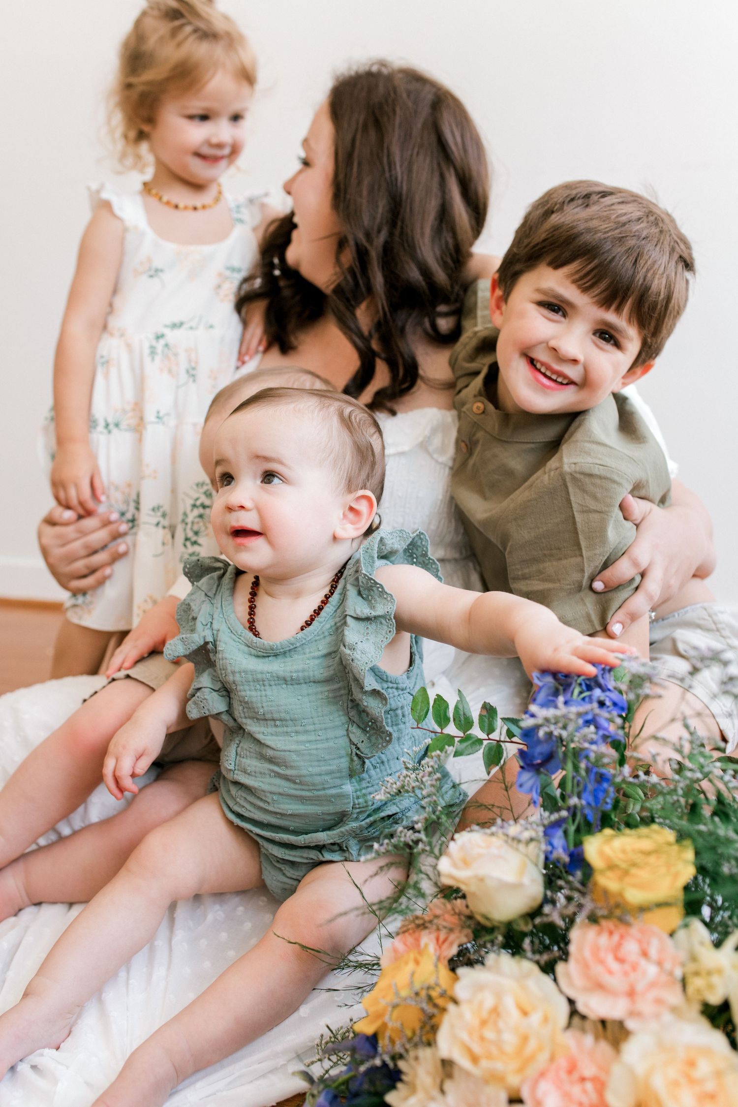 Family portrait with beautiful flowers featuring a tender moment between siblings and parent.