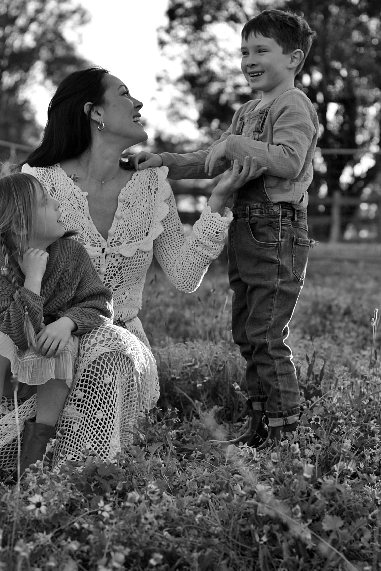 Playful family photo of mum and children sitting together outdoors during a family session
