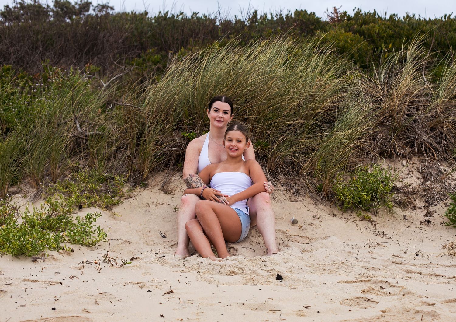 Sweet mother-daughter embrace on grassy headlands during a motherhood session taken by A Lasting Impression Photography.