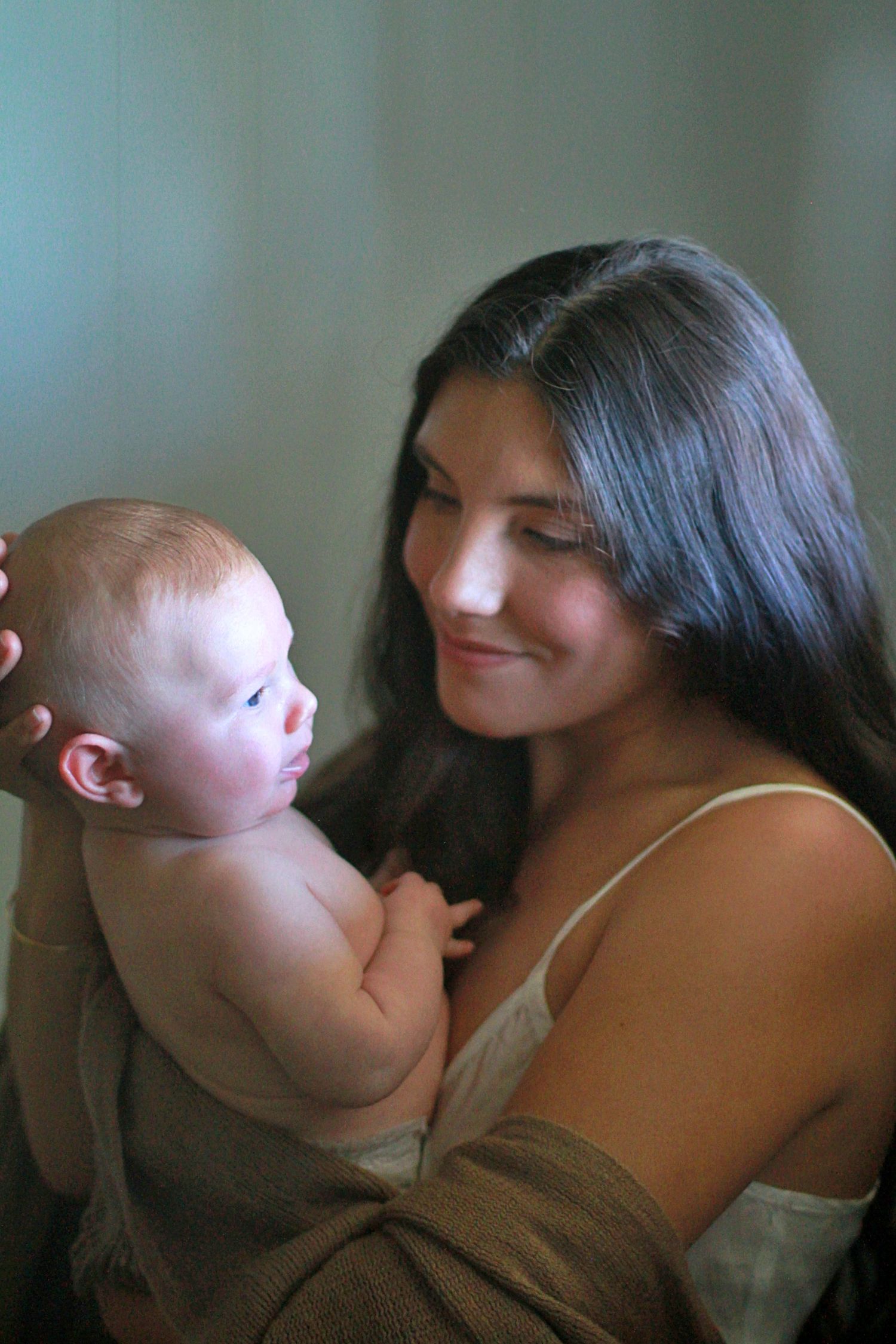 Intimate motherhood moment of a mum cuddling her baby at home by A Lasting Impression Photography.