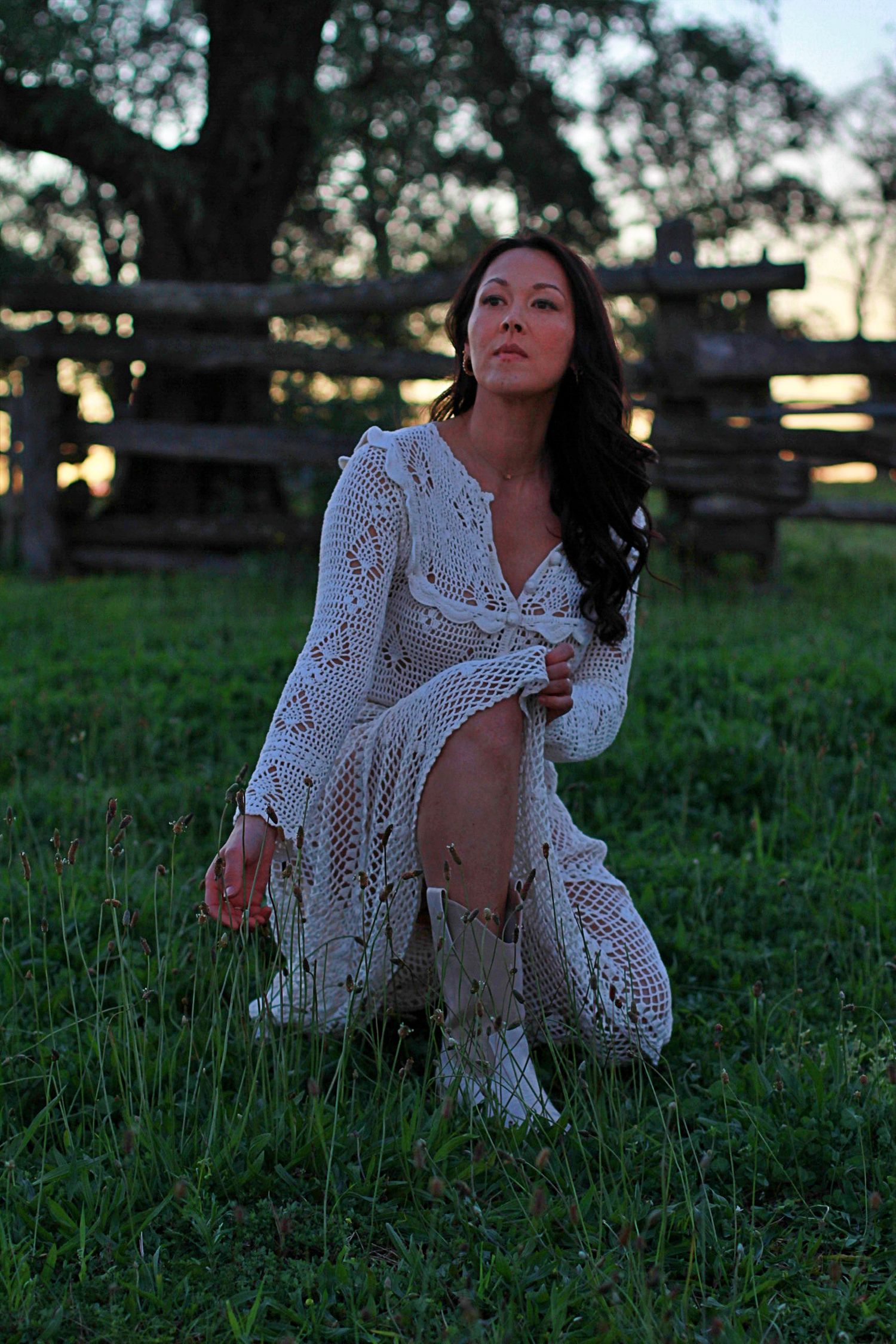 Woman kneeling in tall grass with a serene expression