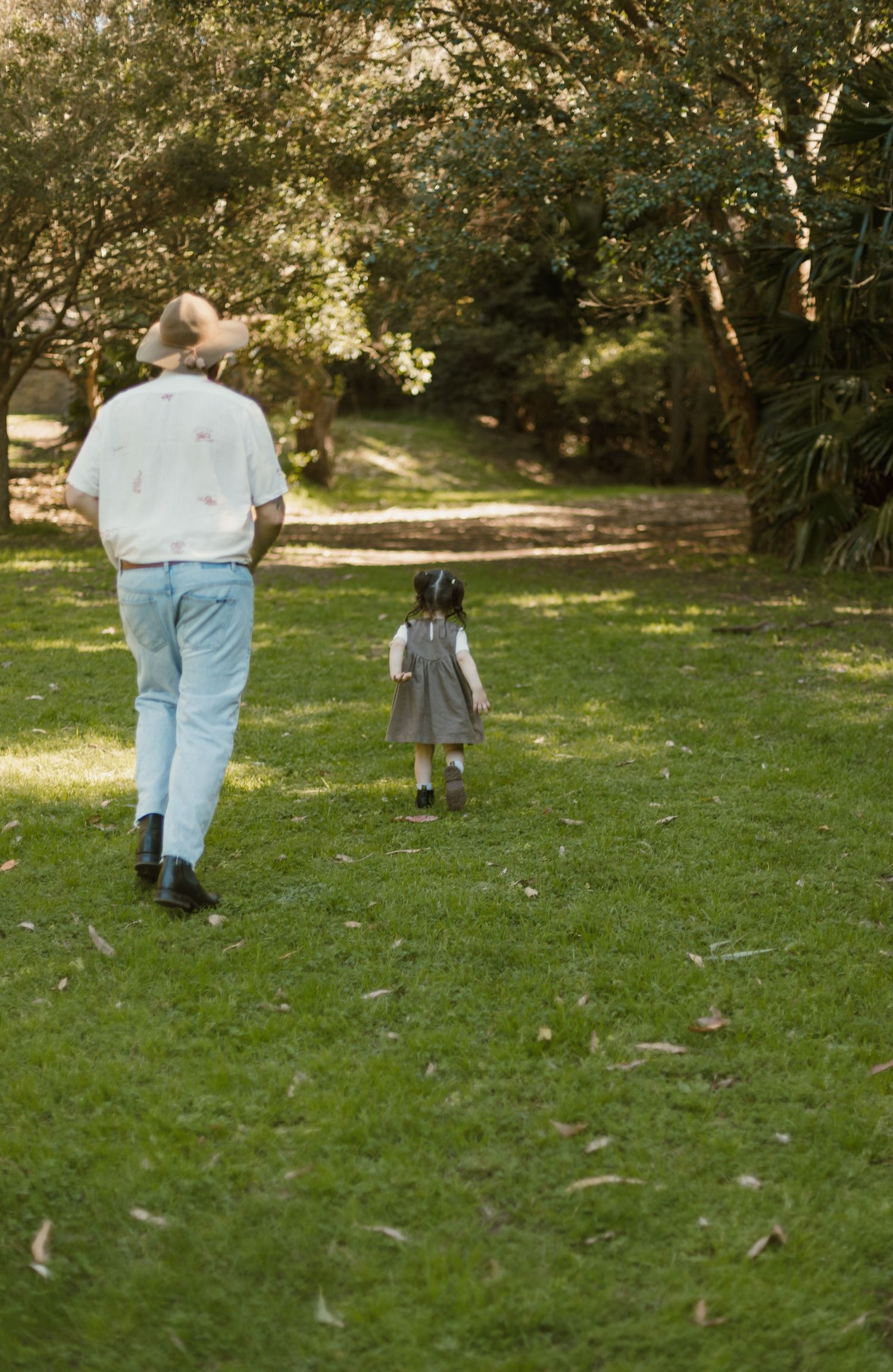 Dad walking across the grass with his young daughter during a relaxed family photography session.