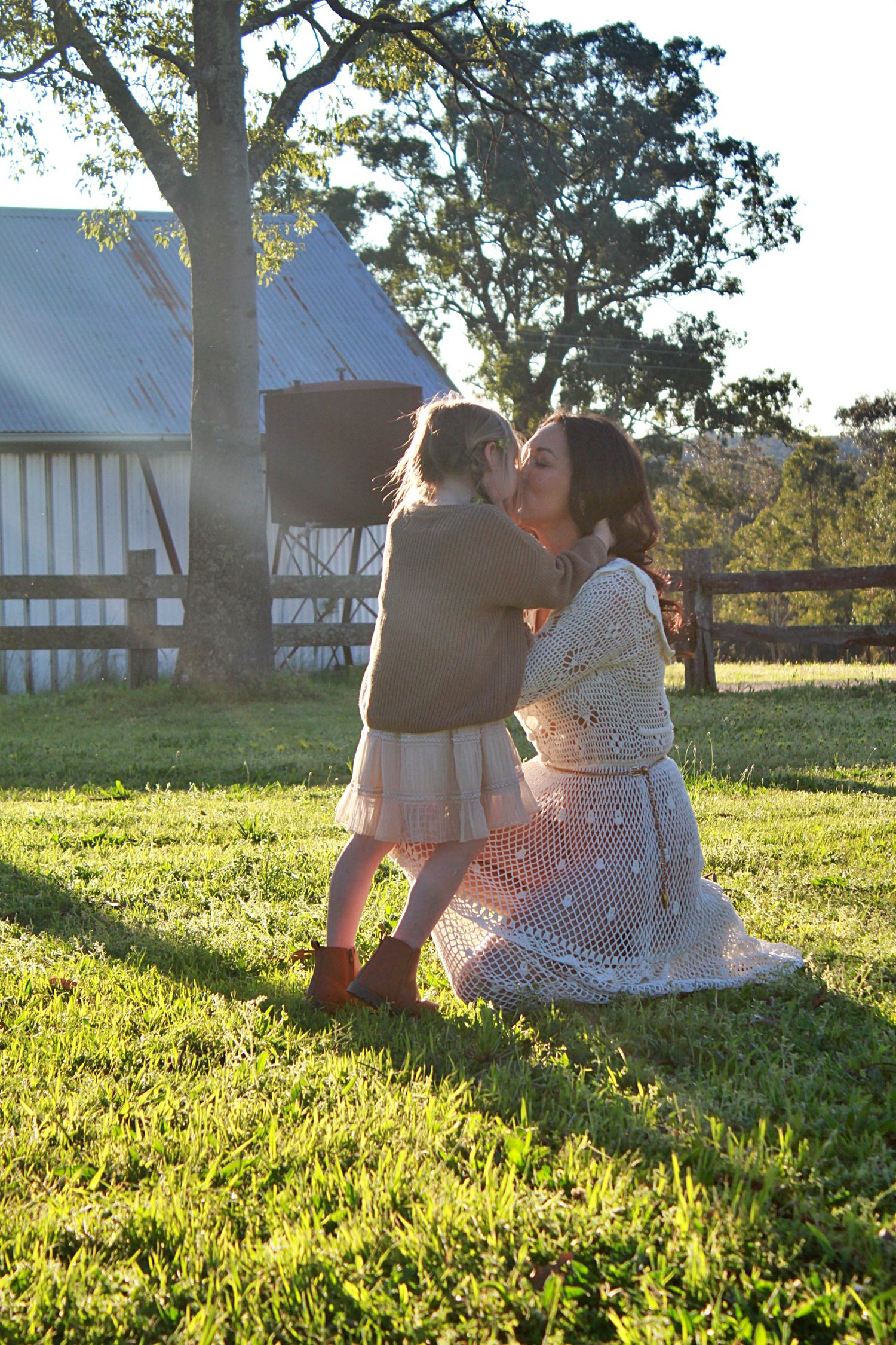 Mum kneeling to connect with her daughter during outdoor family session