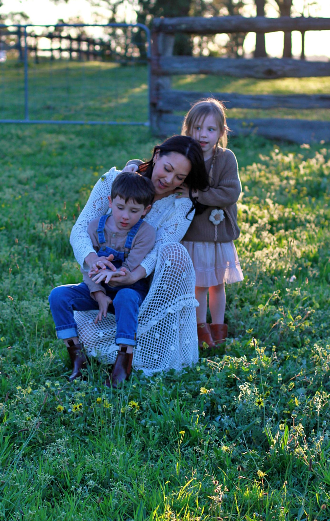 Relaxed family photo of mum and children sitting together outdoors during a family session