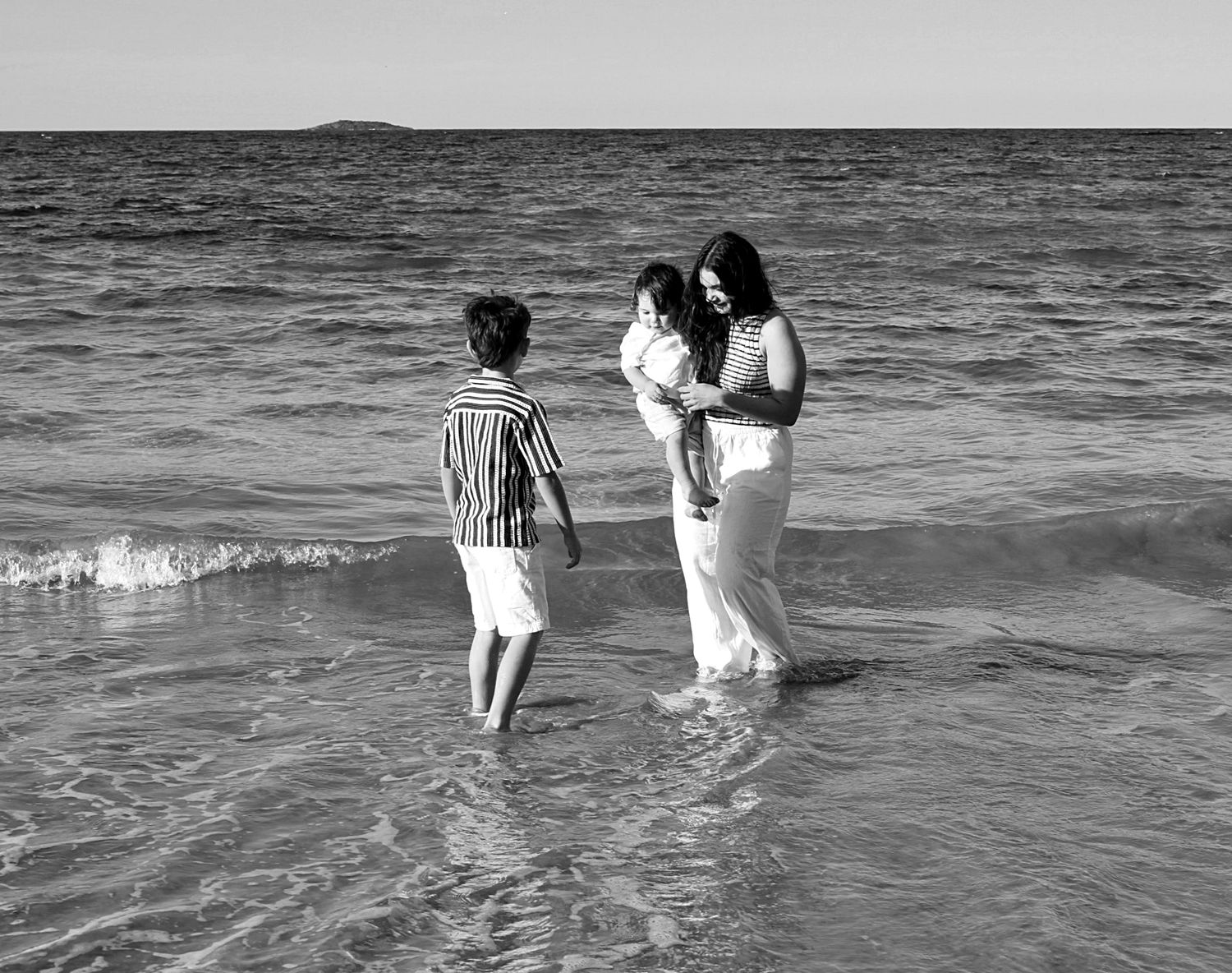 Authentic motherhood moment of a mother and her children connecting through play by the sea.