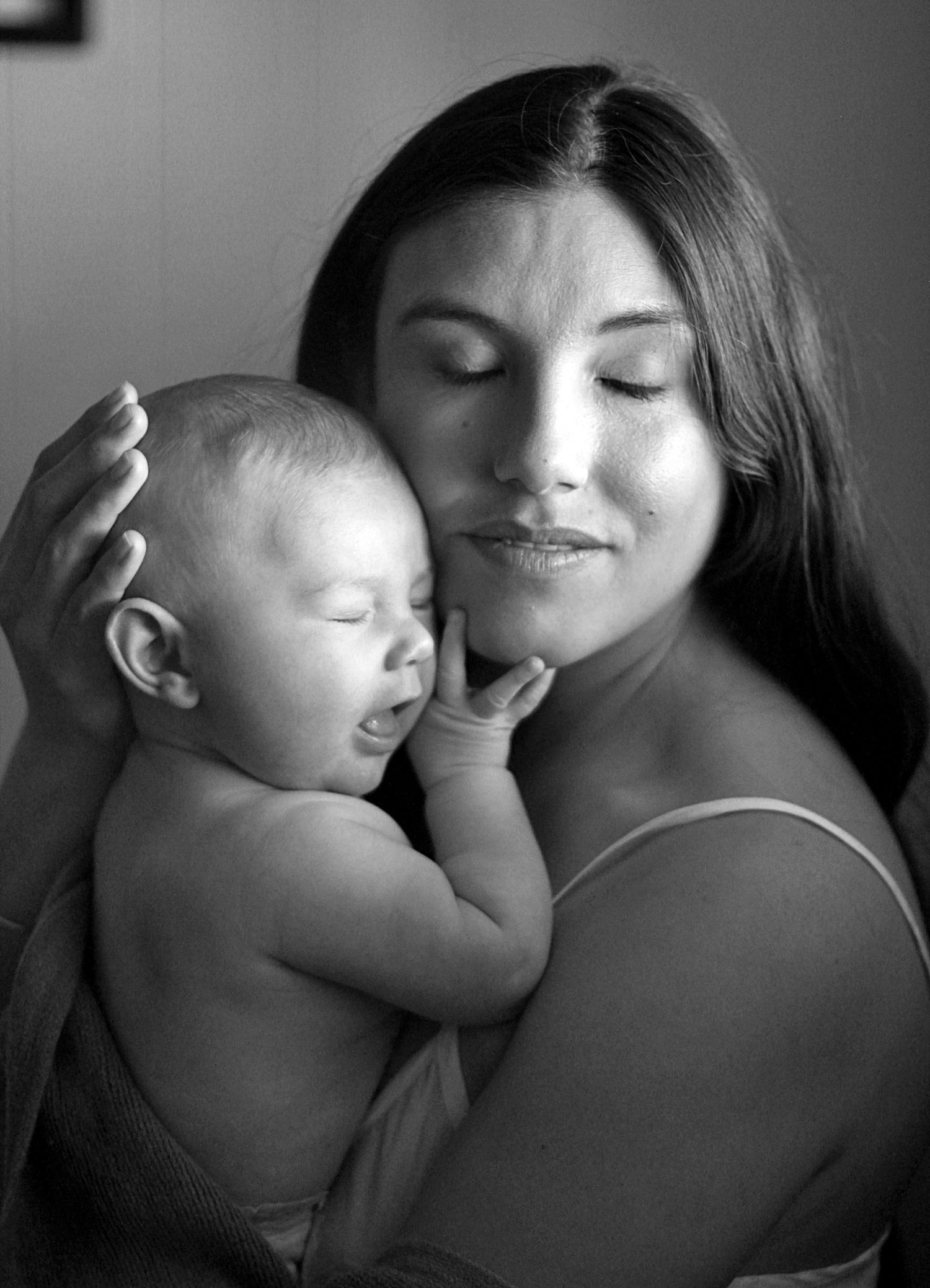 Intimate motherhood moment of a mum cuddling her baby at home.