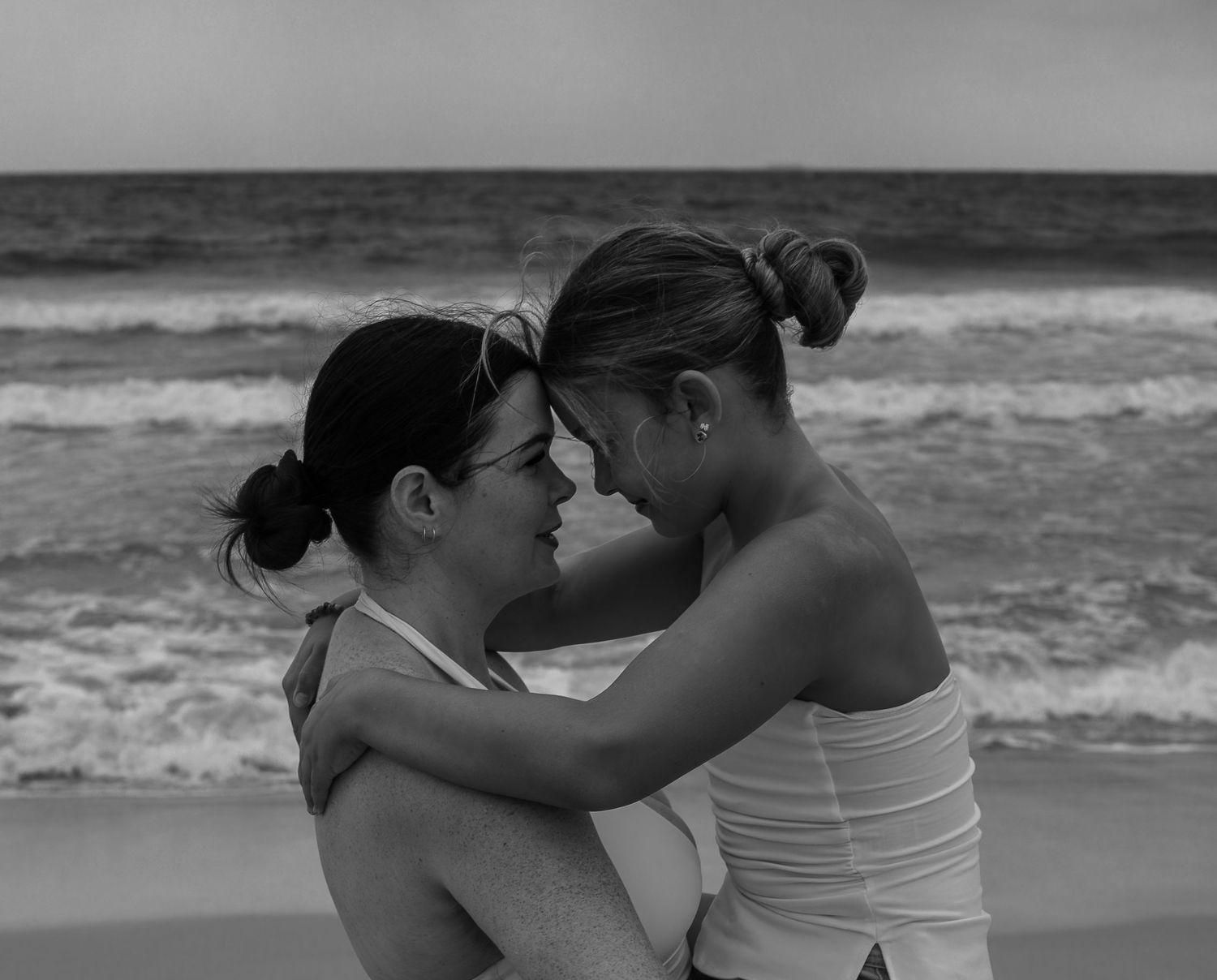 Black-and-white close-up of a mother and daughter touching foreheads, capturing a tender and intimate motherhood moment.