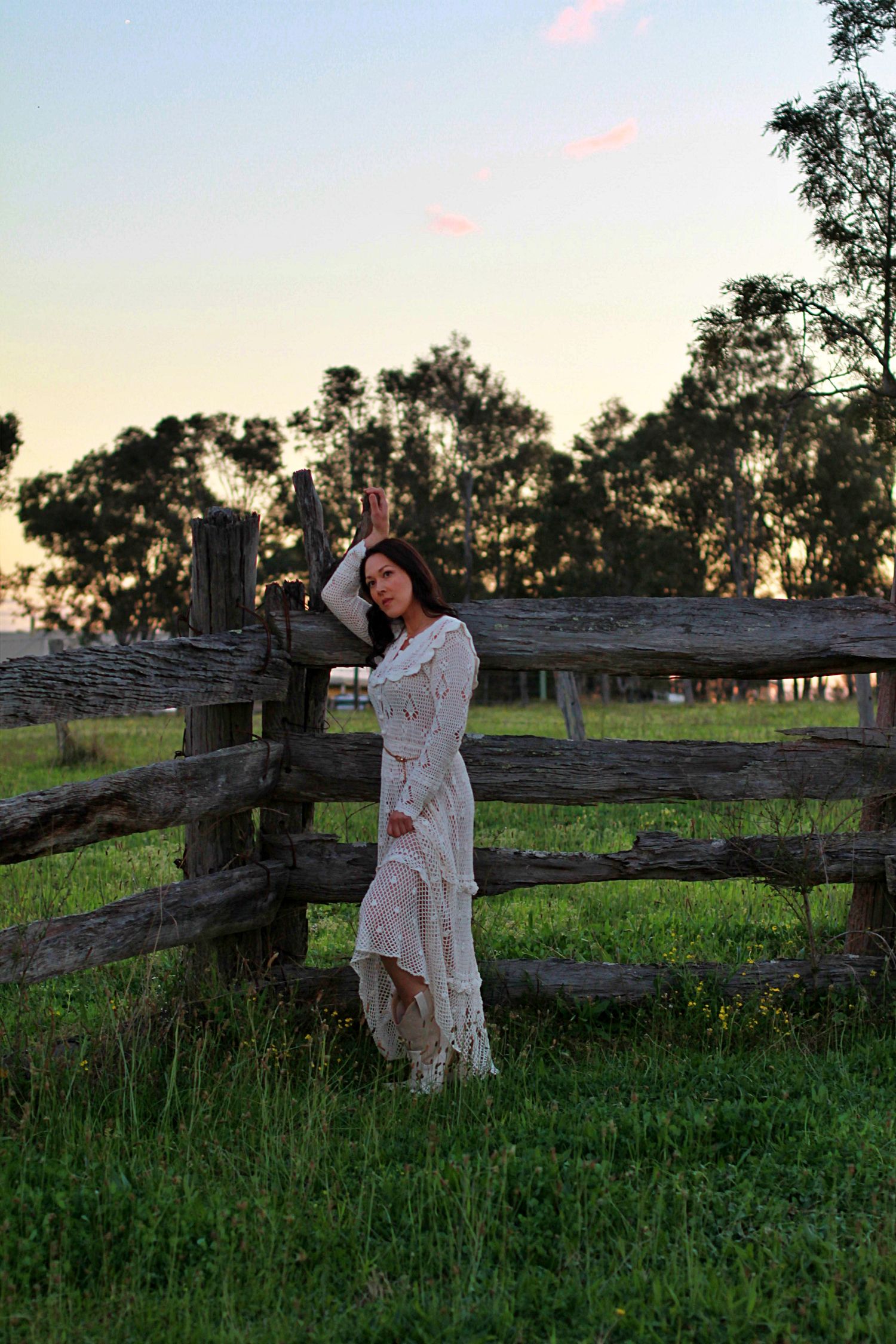 Elegant outdoor portrait of a woman leaning on a fence