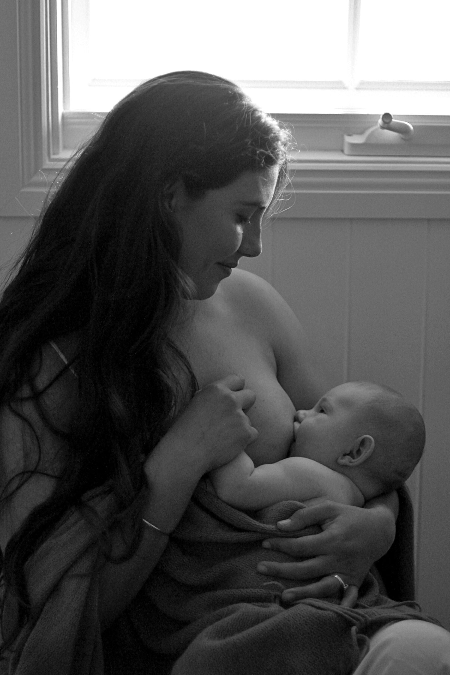 Mother breastfeeding her baby during a natural lifestyle motherhood session at home by A Lasting Impression Photography.