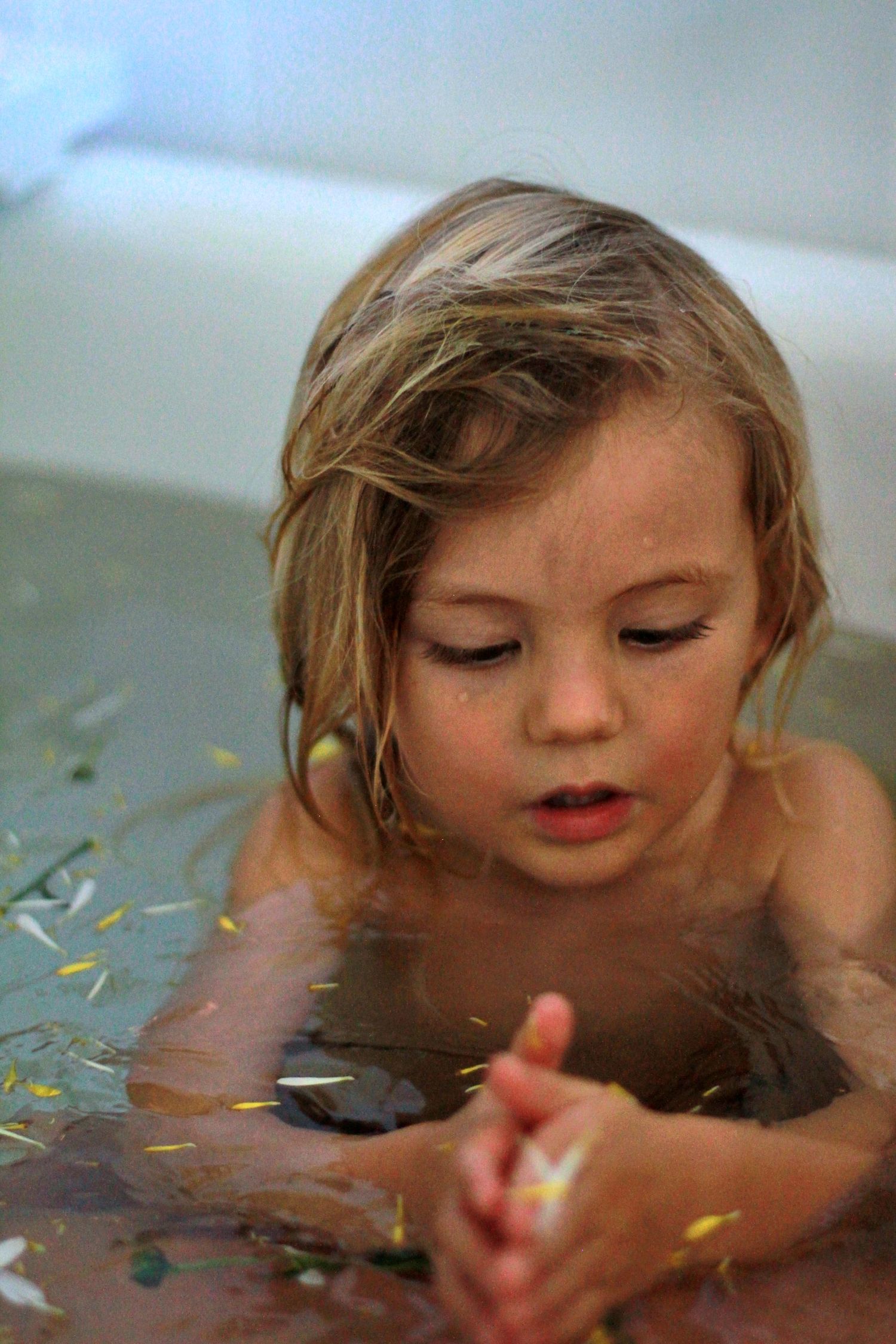 Young boy splashing in the bath during a lifestyle motherhood session at home by A Lasting Impression Photography.