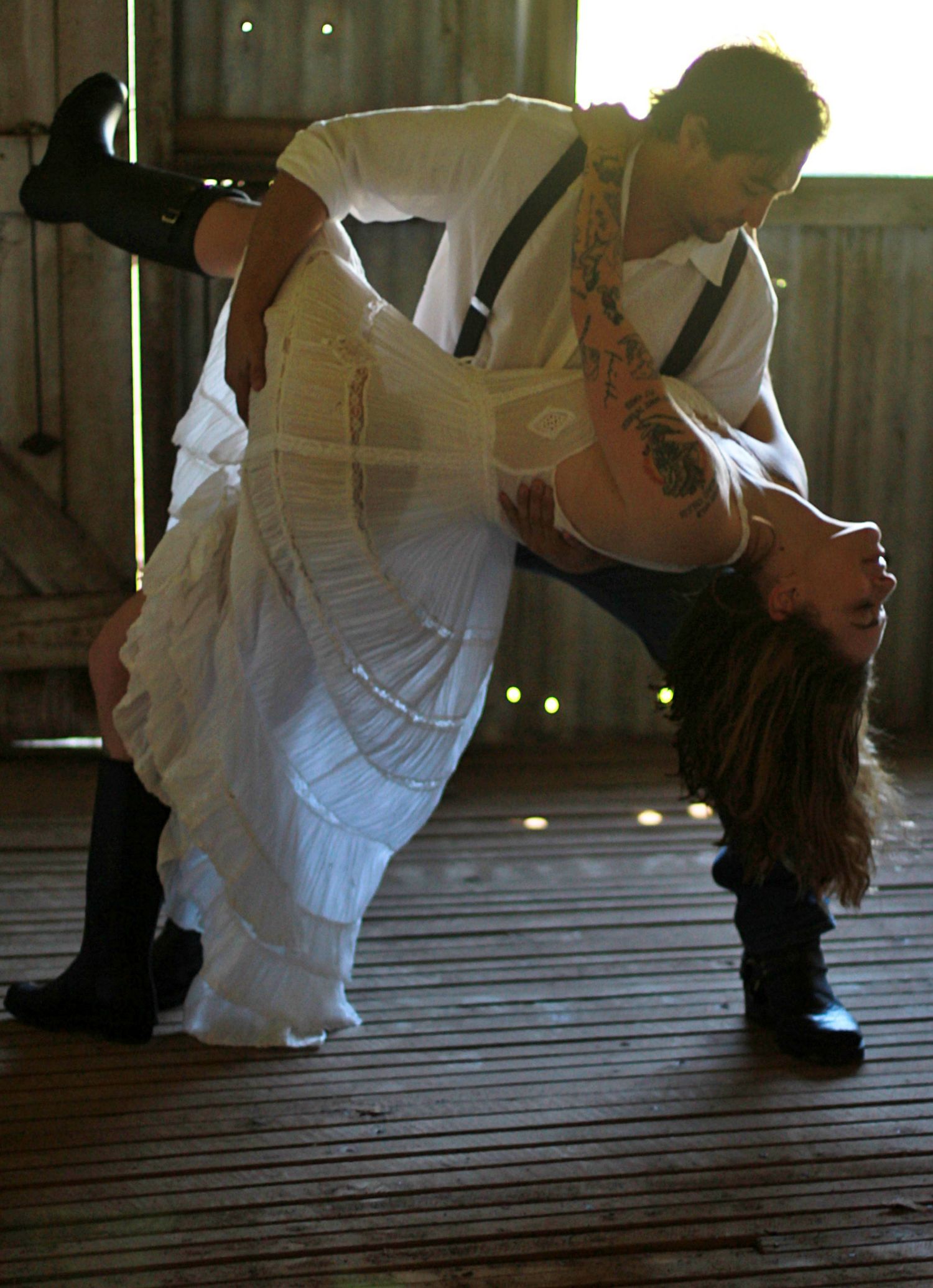 Romantic engagement photos of a couple dancing together inside a rustic barn