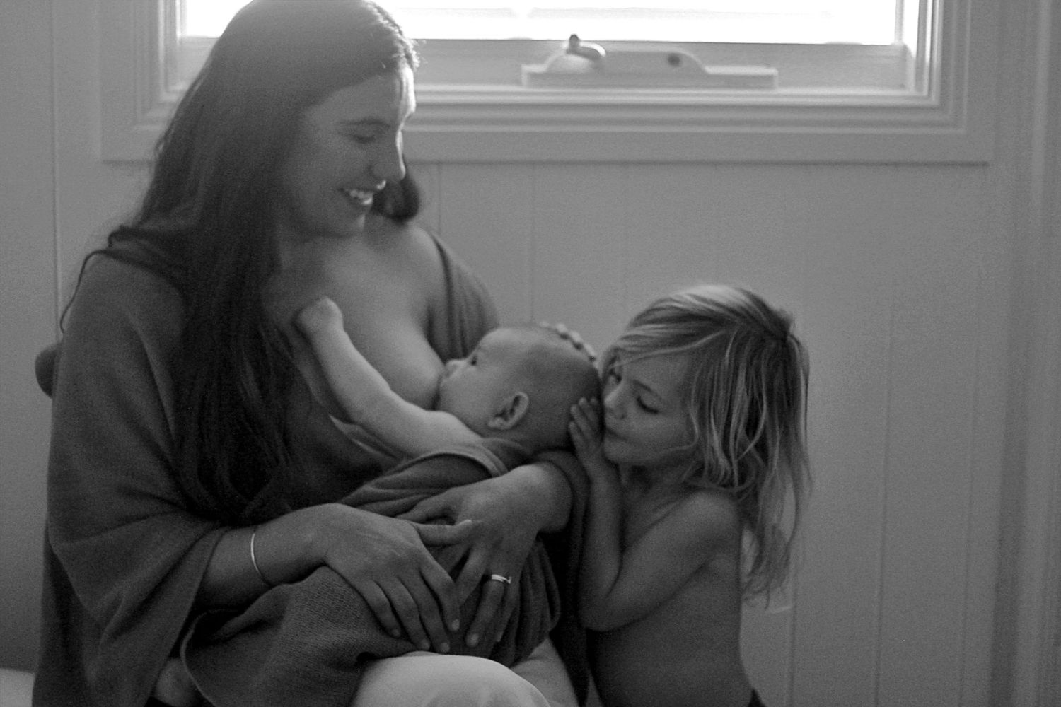 Candid black and white moment of big brother cuddling sibling in a lifestyle motherhood photoshoot by A Lasting Impression Photography.