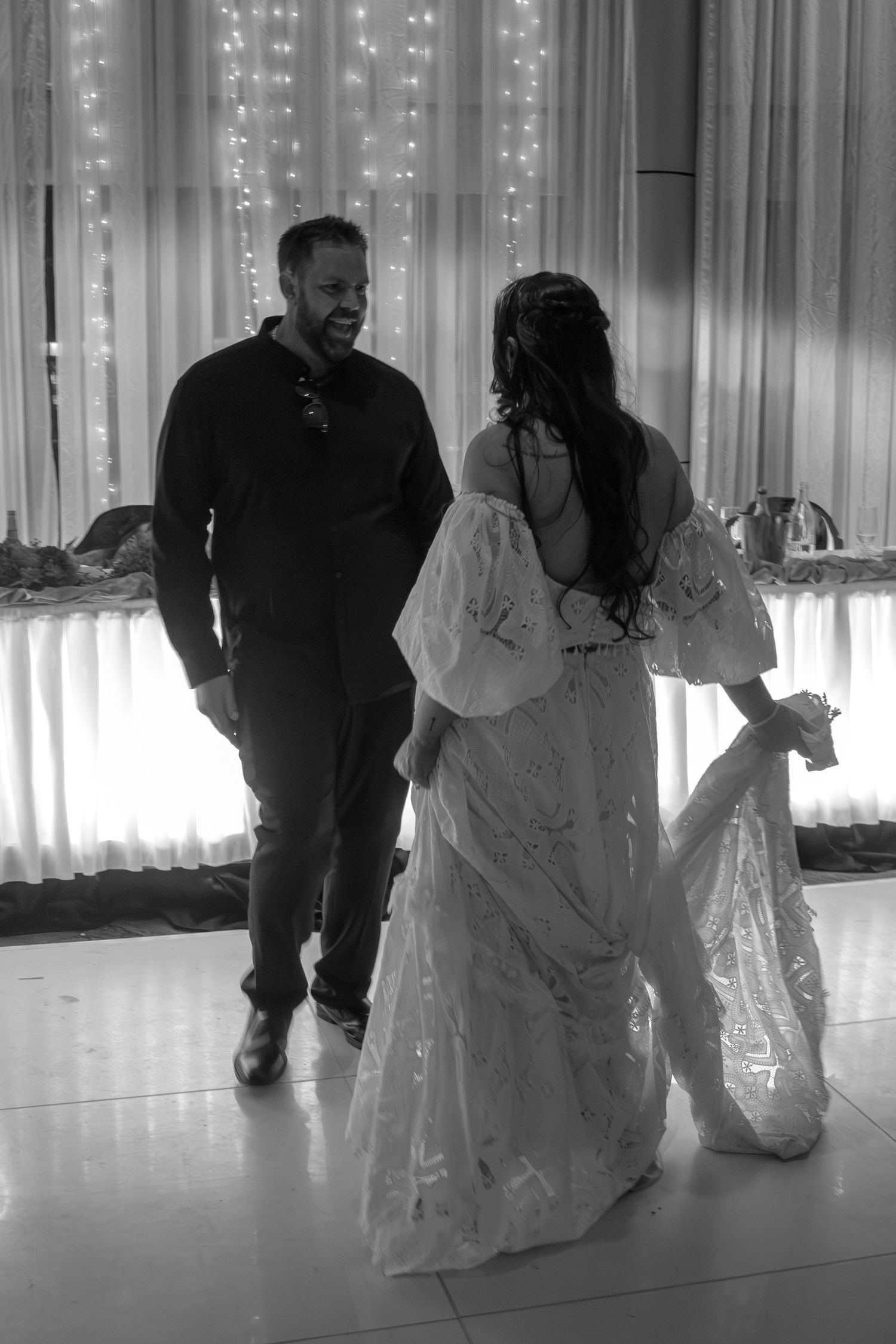 Candid wedding photo of the bride and groom dancing, with the groom smiling at his bride during their joyful celebration.
