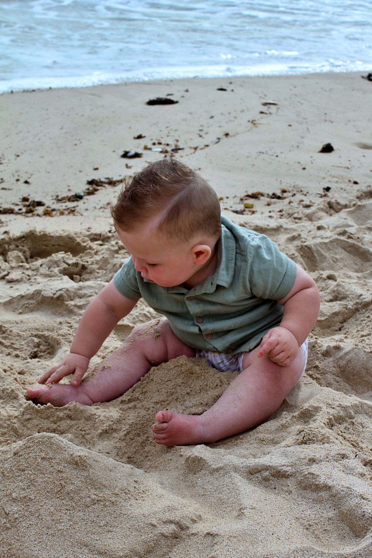 A candid portrait of a son playing in the sand on the beach in the Illawarra, full of curiosity and fun.