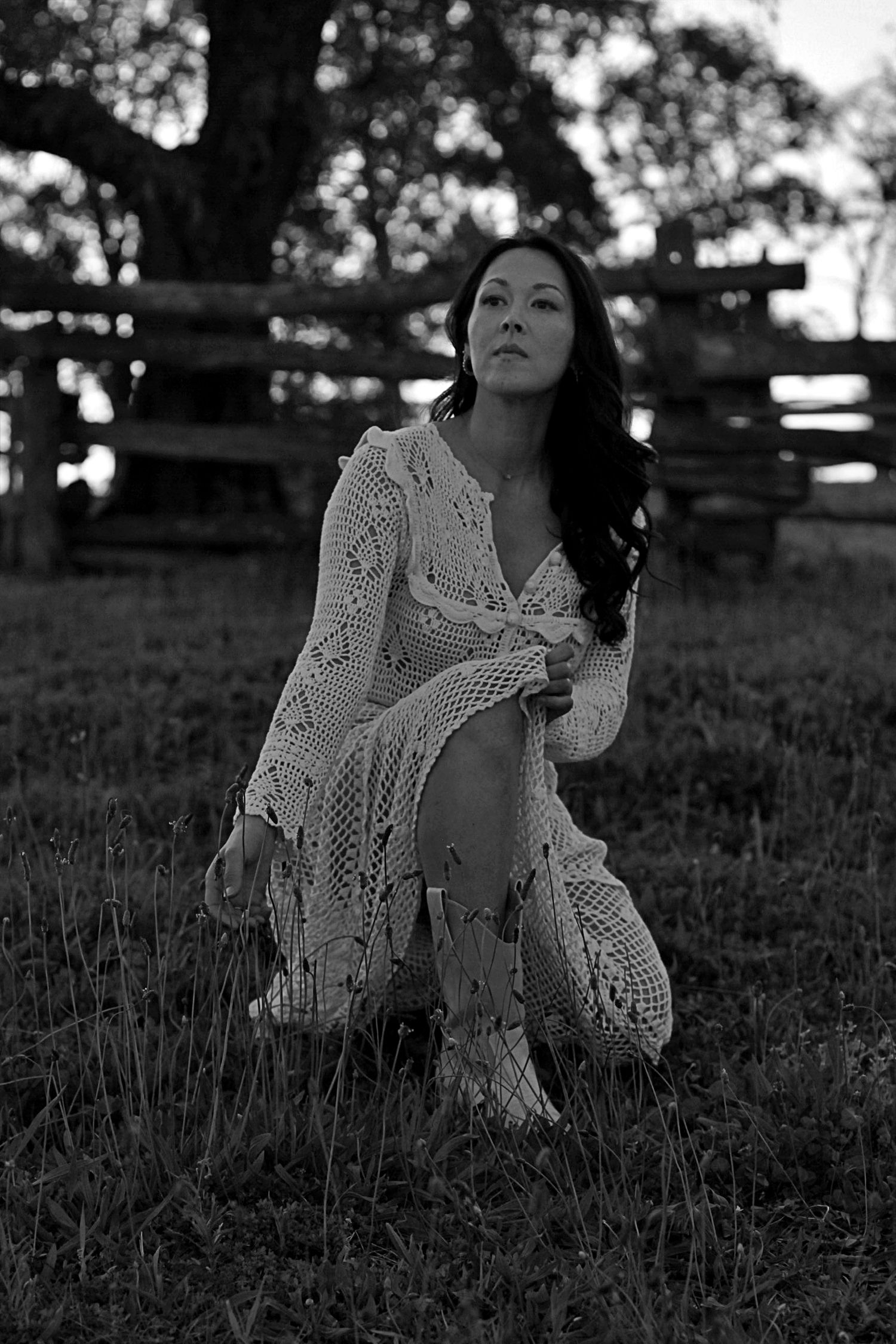 Woman kneeling in tall grass with a serene expression