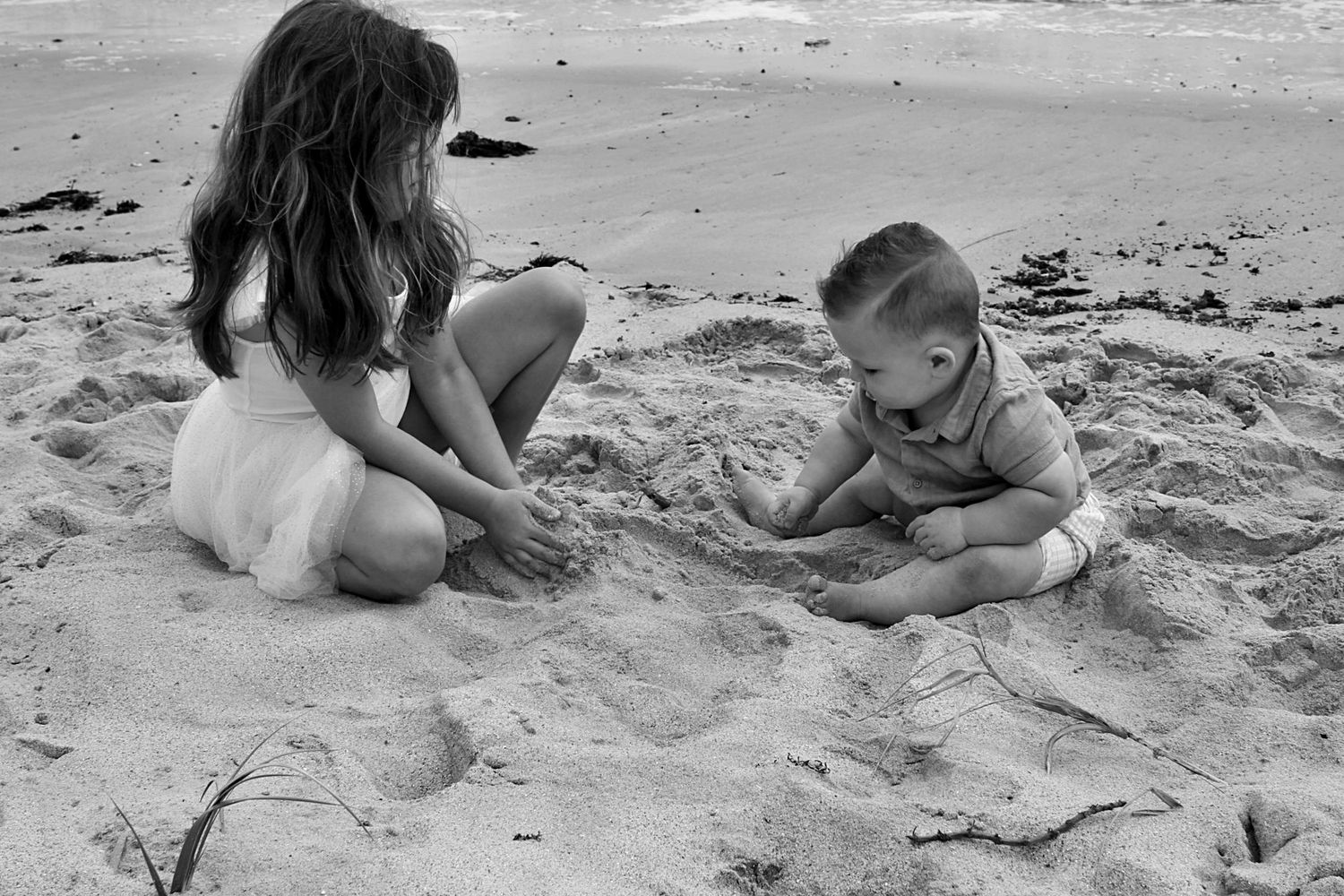 Brother and sister playing together in the sand on the beach in the Illawarra, capturing joyful sibling connection.