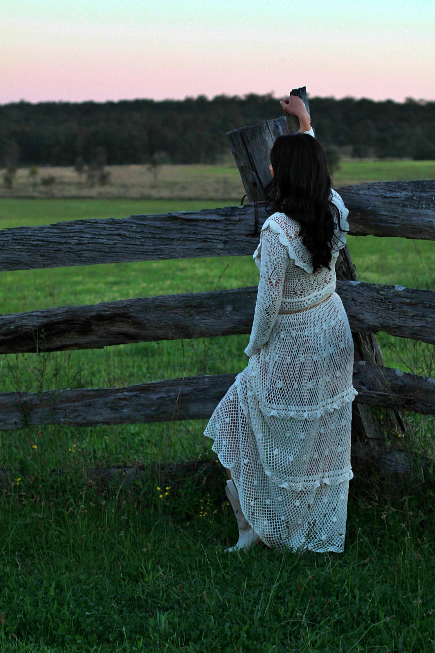 Elegant outdoor portrait of a woman leaning on a fence looking away