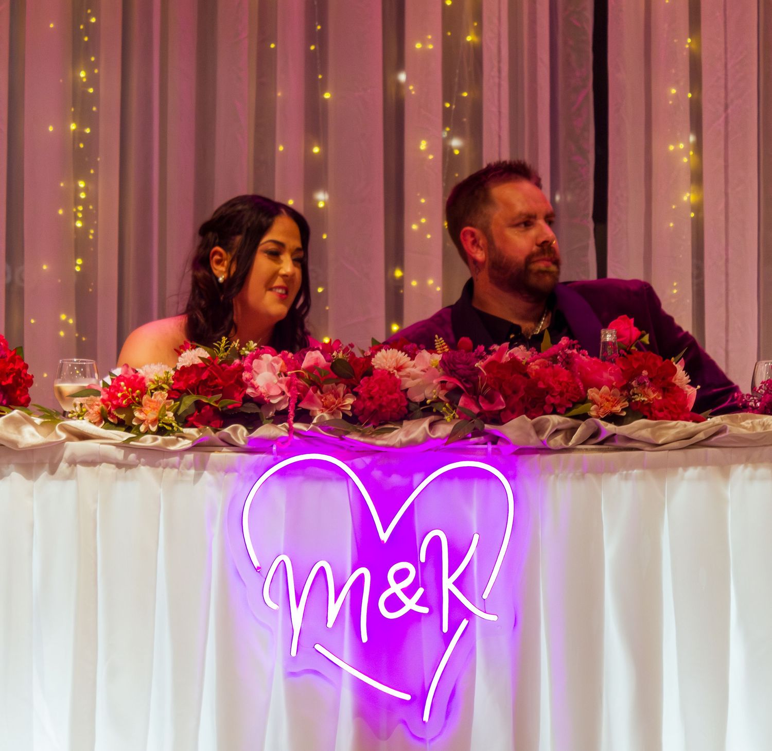 Close up of the bride and groom seated together at the reception table.