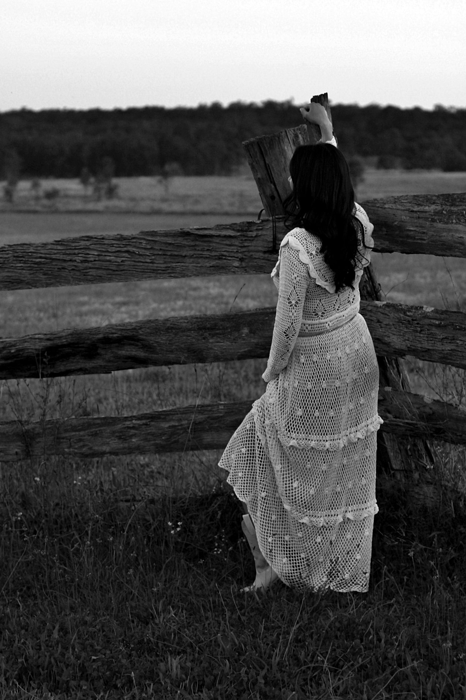 Elegant outdoor portrait of a woman leaning on a fence looking away