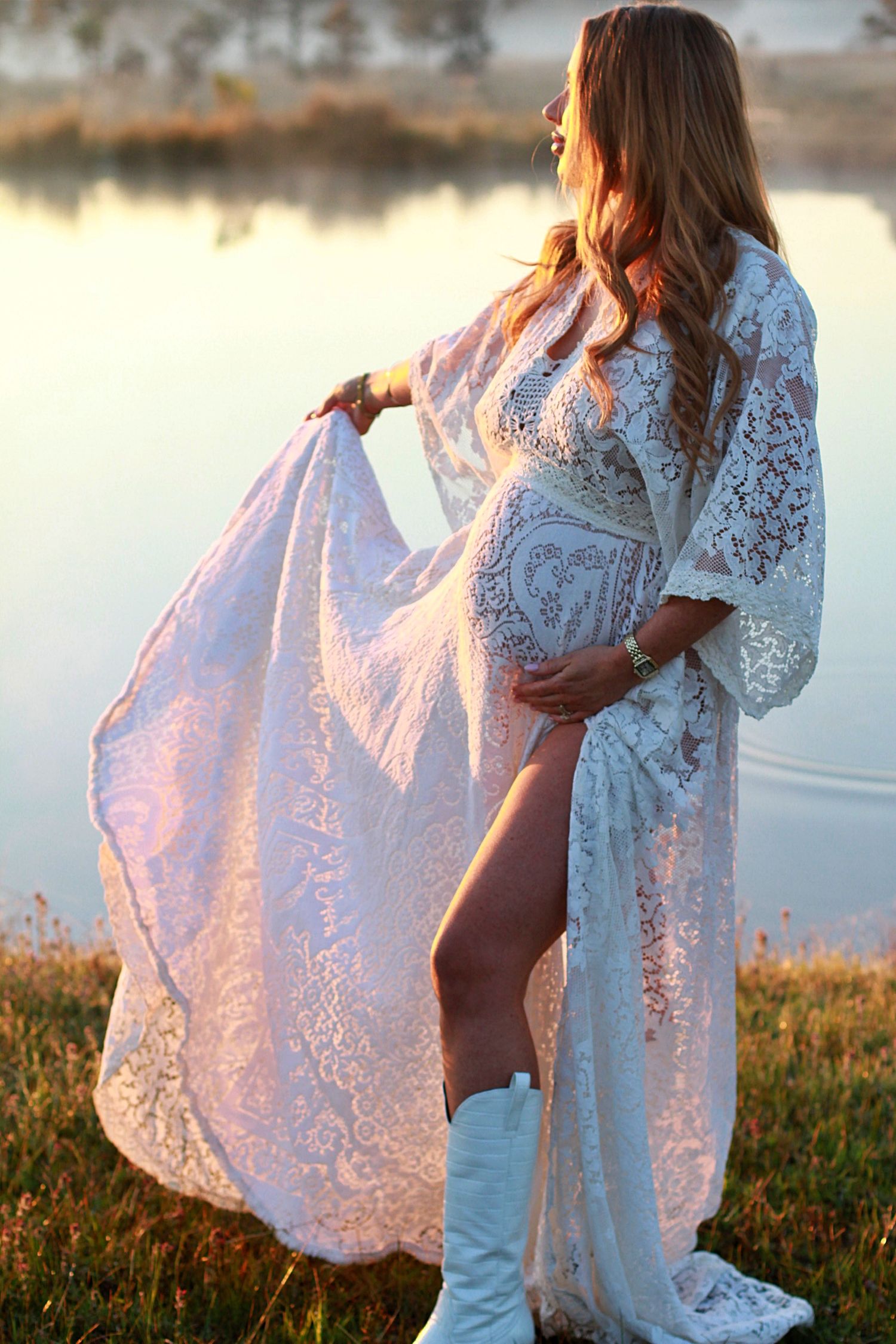 Expecting mum captured at sunrise, looking out to the sunrise holding her dress.