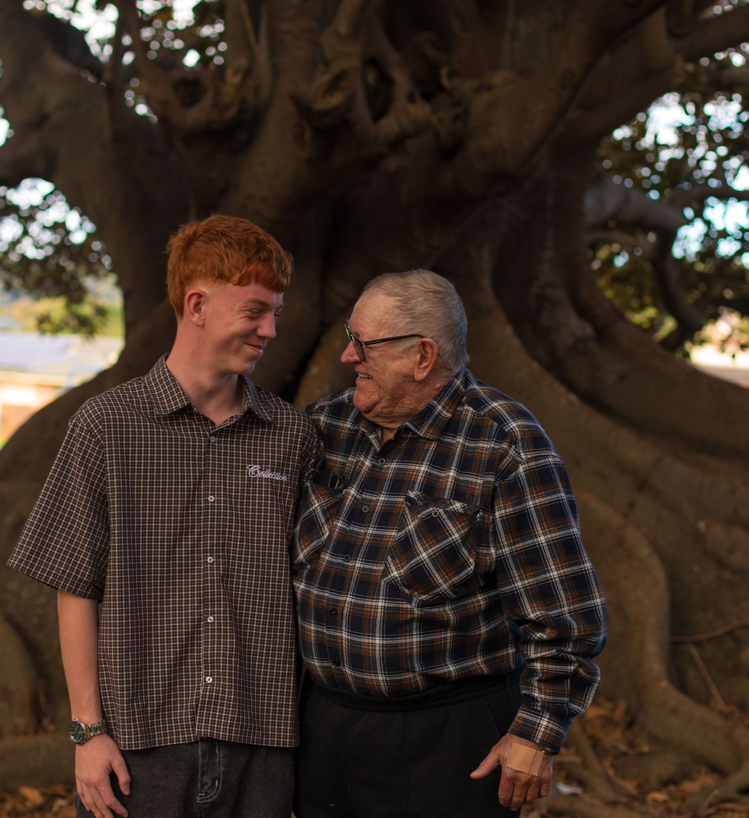 Grandfather and grandson smiling at each other during an outdoor extended family photography session.