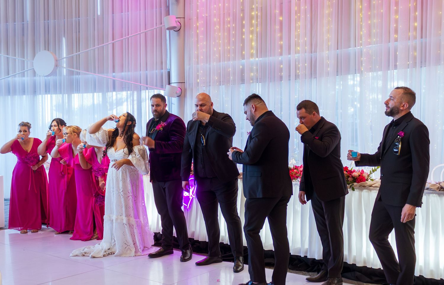Bridal party taking shots on their grand reception entrance, fun wedding celebration moment.