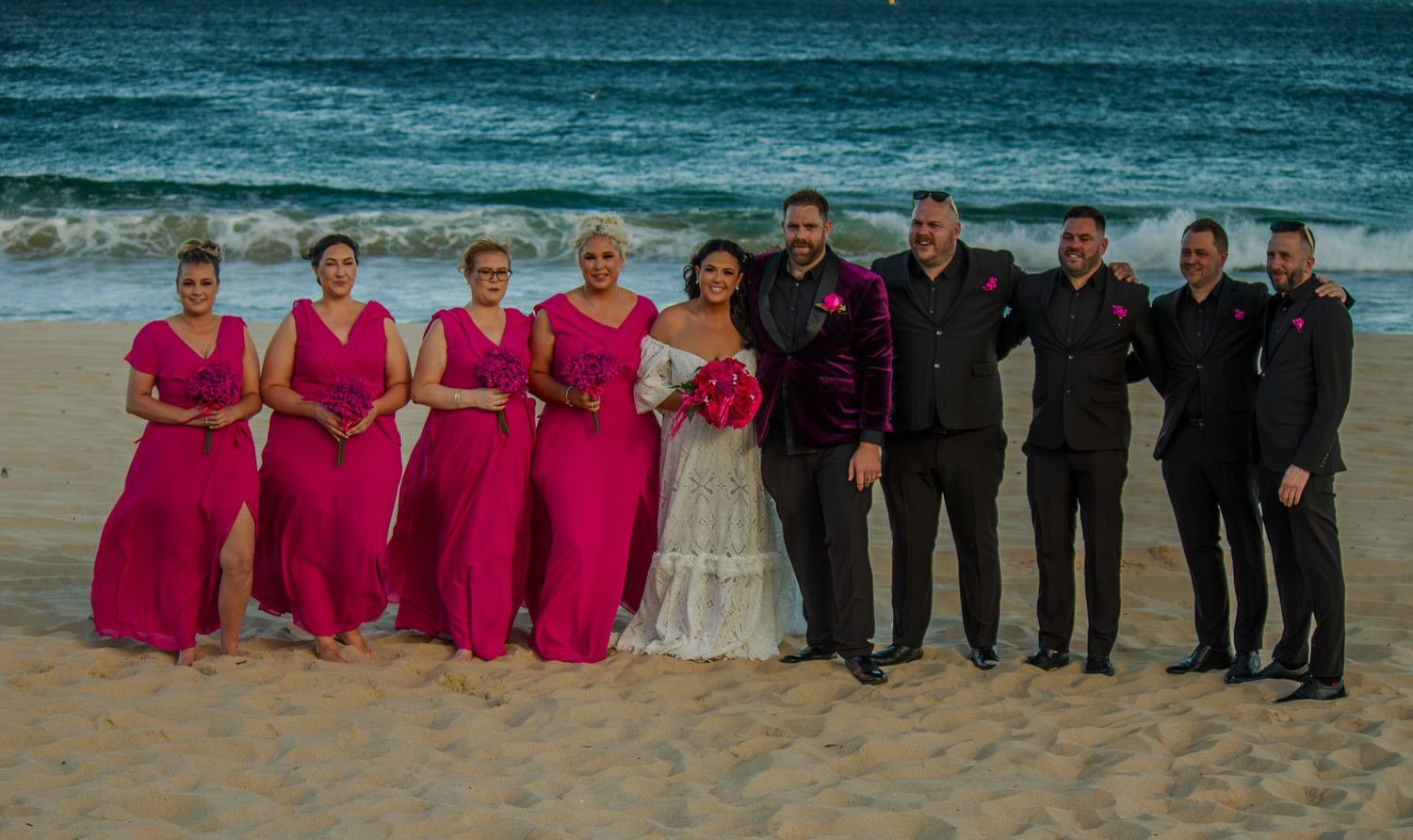 Bride, groom, bridesmaids and groomsmen portrait on the beach.